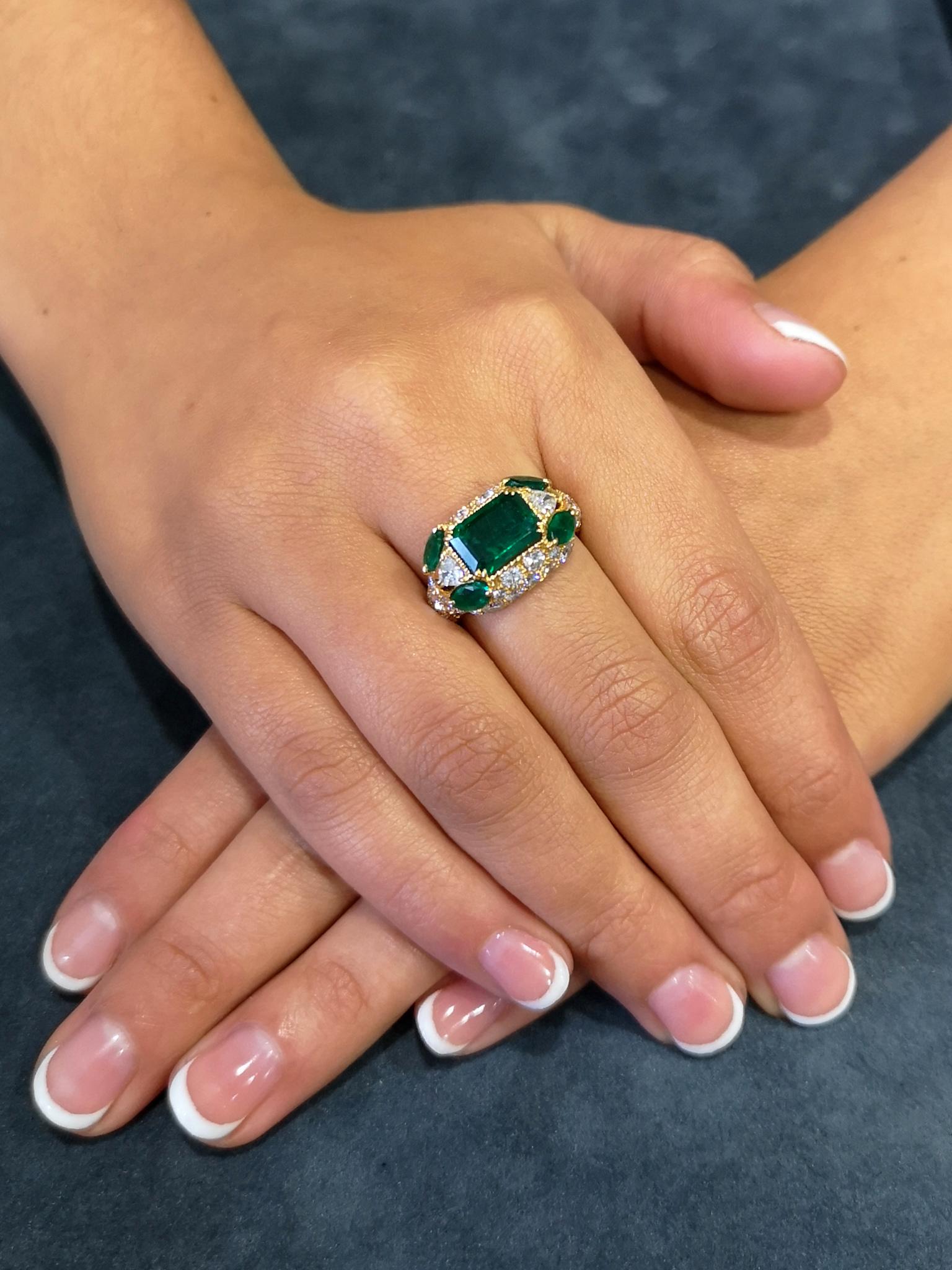 Fashioned from the finest quality emeralds and diamonds and mounted in 18-carat gold, a dazzling ring by famed Paris jewellery designer Alexandre Reza. The central bottle-green emerald of approximately 2.25 carats, set into a raised 'cushion',