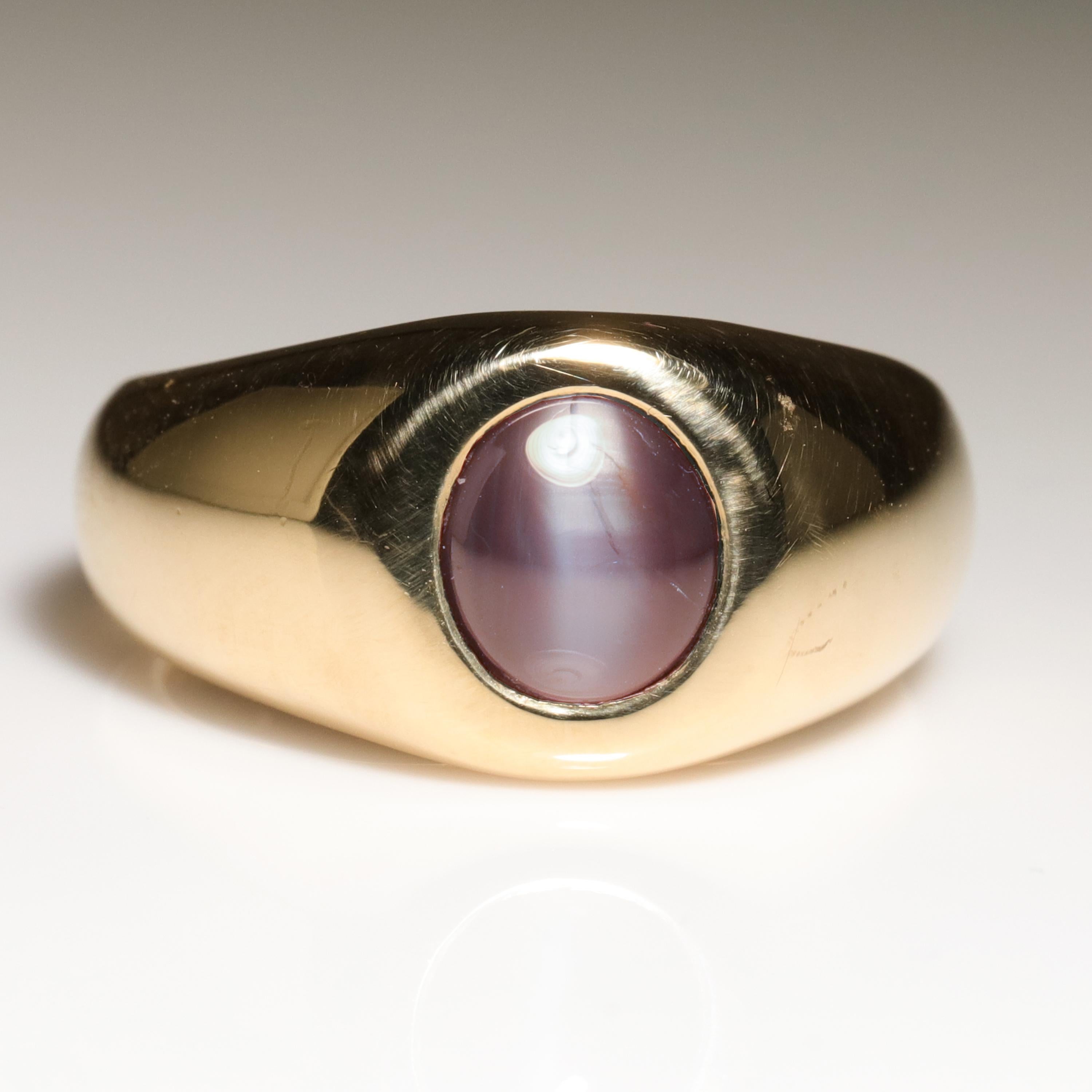 This dense and weighty (16.91 grams) men's pinkie ring is crafted in solid 18K yellow gold and features a natural and untreated alexandrite cat's eye gem, measuring approximately 7.65 mm x 6.84 and weighing about 1.30 carats. You may be familiar