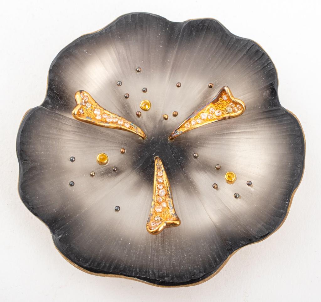 Group lot of four Alexis Bittar brooches, one daisy with gold-tone metal stem, one frosted pink lucite flower pin, one fuschia flower mounted with orange gemstones, and one black lucite flower with inset rhinestones, all marked.

Dealer: S138XX
