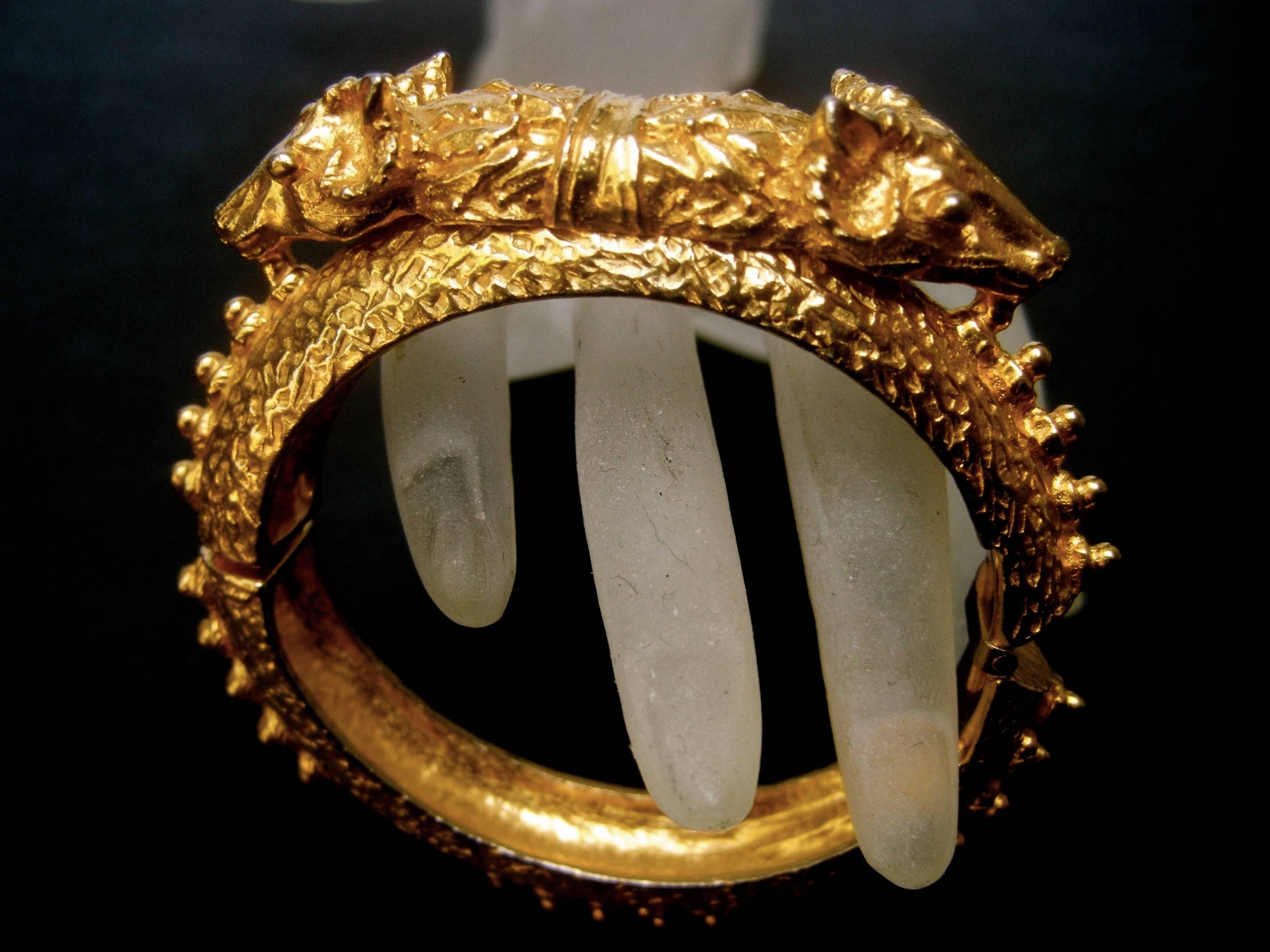 Alexis Kirk ornate gilt metal etruscan style hammered hinged bracelet 
The heavy gilt metal bracelet is designed with a pair of stylized
rams heads at the center

Circling the bracelet band are a series of spike grommets
The interior is stamped