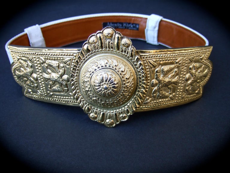 Alexis Kirk Massive ornate Etruscan style embossed white leather belt c 1980s
The ornate large scale gilt metal buckle is designed with a huge circular medallion in the center

The gilt metal side panels are designed with stylized repousse'
