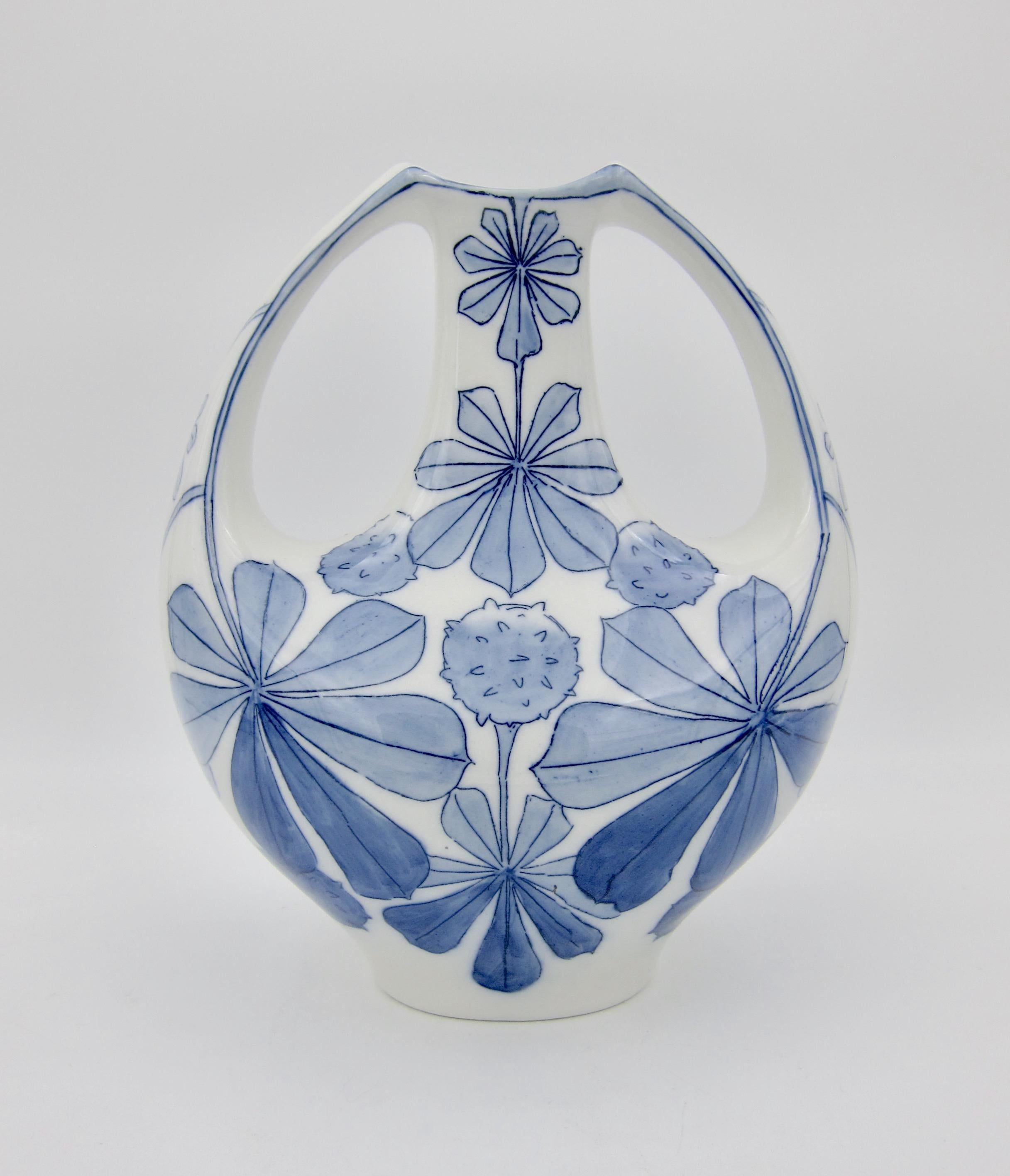 An early 20th century Art Nouveau vase designed by Alf Wallander for the Rörstrand Factory of Sweden, circa 1904. The two handle porcelain vase features a Jugendstil decor scheme of chestnut leaves and pods hand-painted in an inky blue on a white