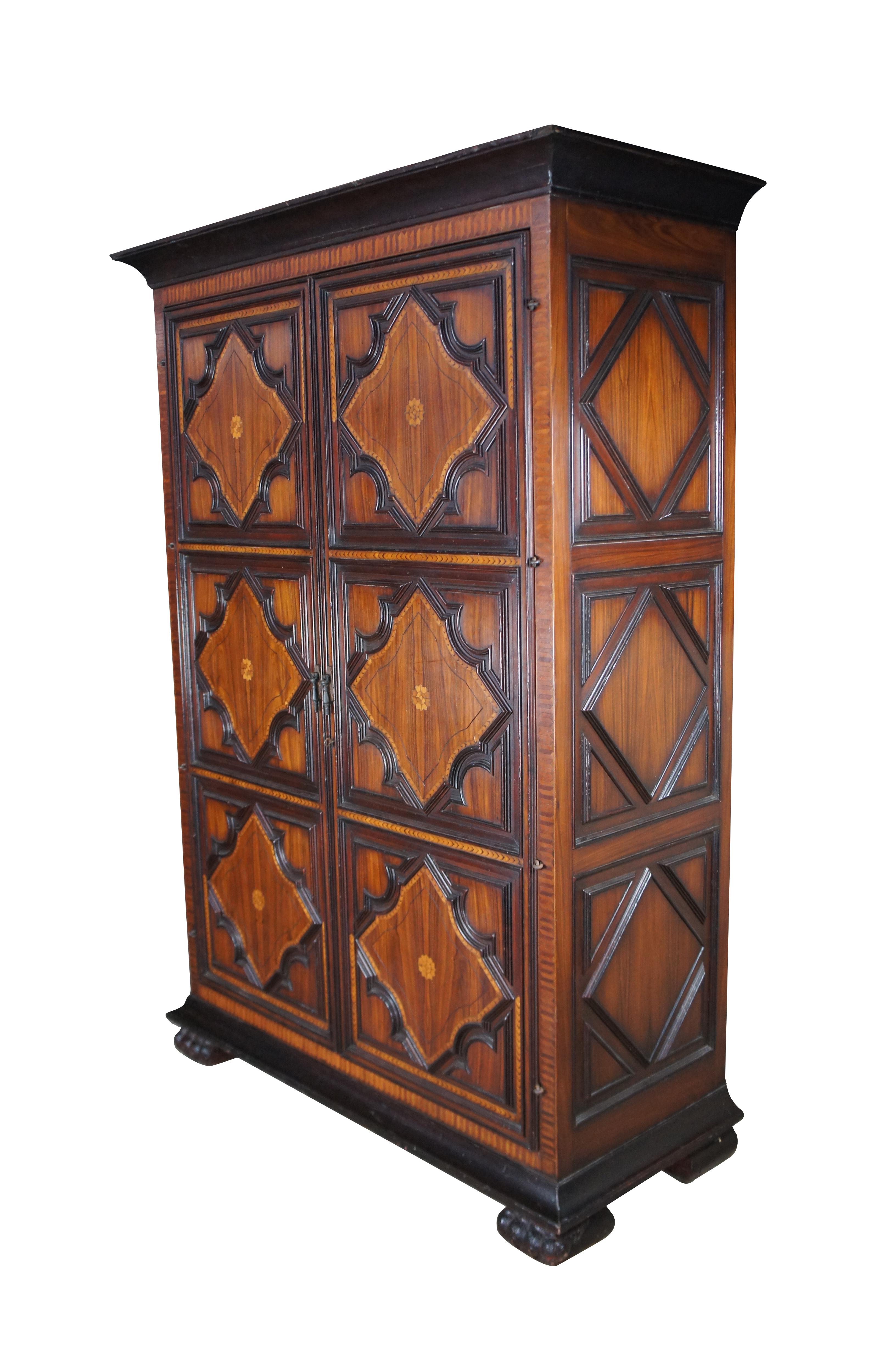 A breathtaking wardrobe by Alfonso Marina. Drawing inspiration from 18th Century designs with French Louis XIII and Spanish Colonial styling. The armoire is constructed from rosewood and mahogany with fruitwood marquetry and herringbone inlay.