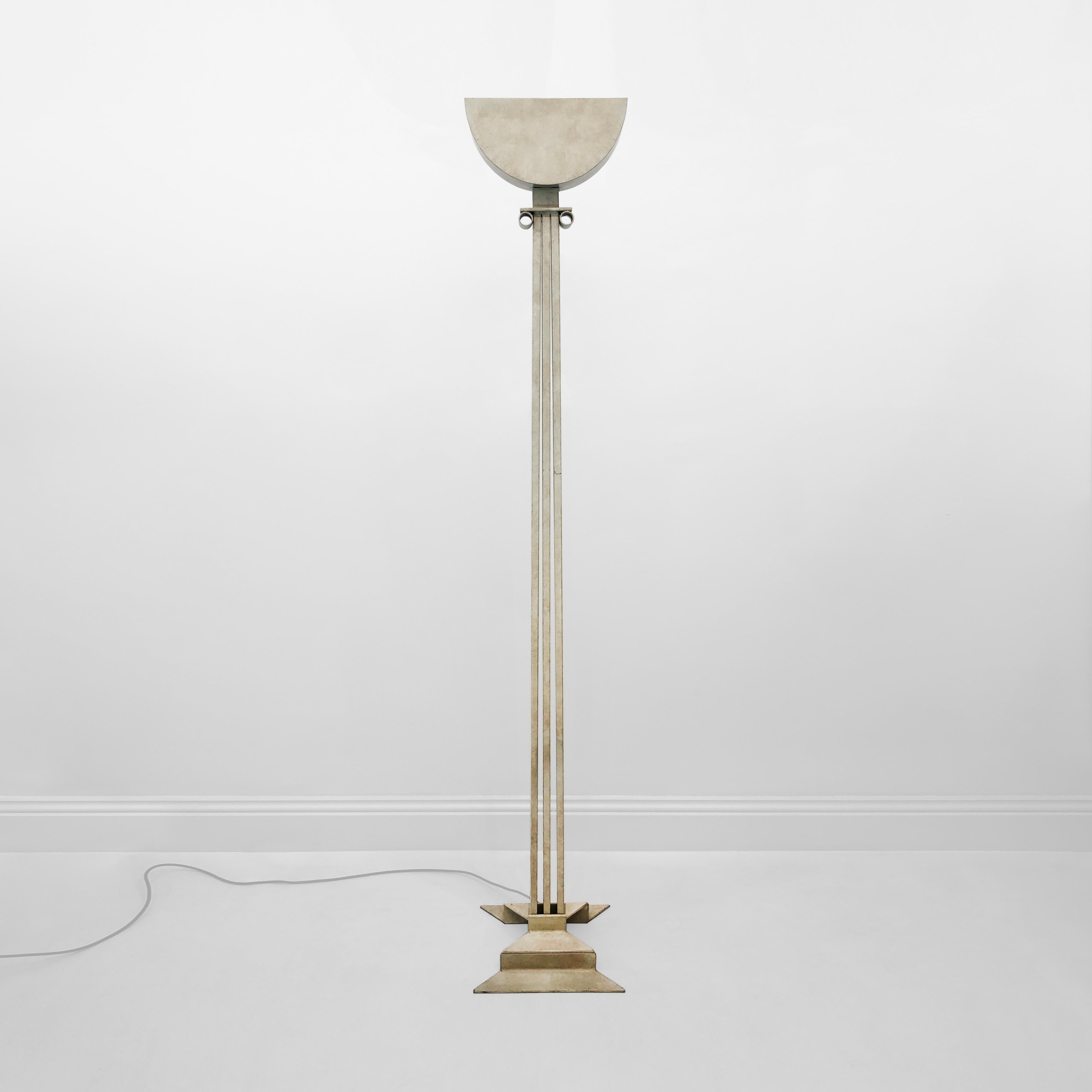 This impressive floor lamp is a playful, post-modern look at neoclassicism. The base is shaped like a bow, and from that protrudes three straight columns, meeting at an ionic head. A half-moon uplighter completes the piece, which is made entirely of