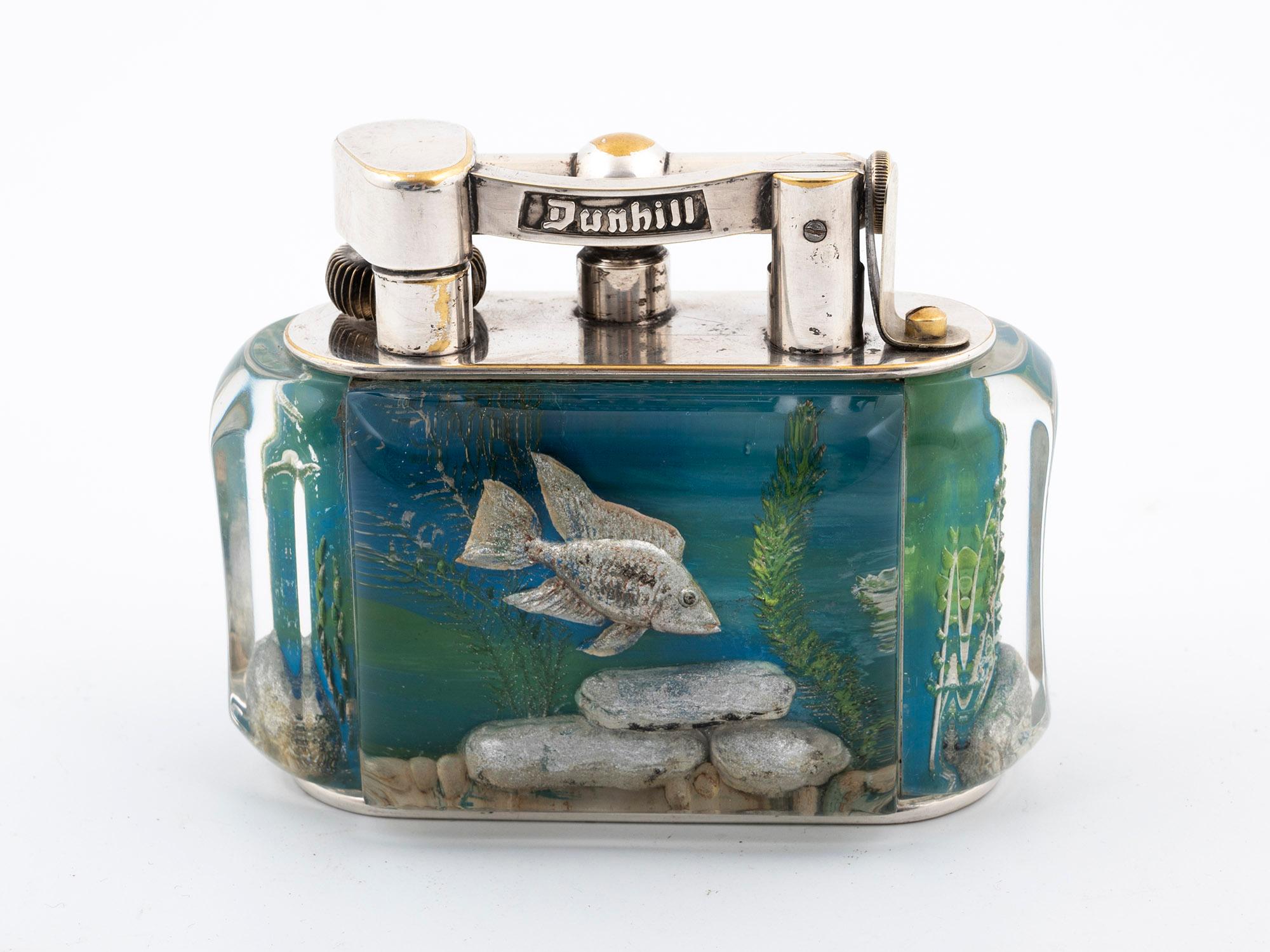 Here, we have an Aquarium Silver-plated Table Cigarette Lighter by Alfred Dunhill.

This 