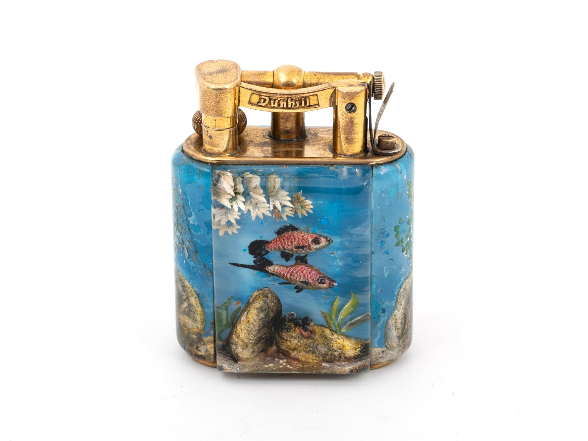 Briquet aquarium d'Alfred Dunhill.

Ce charmant briquet d'aquarium bleu vif possède des panneaux en lucite sculptés à l'envers et peints à la main, ce qui rend chaque scène sous-marine unique. Les poissons rose vif de cet exemple sont extrêmement