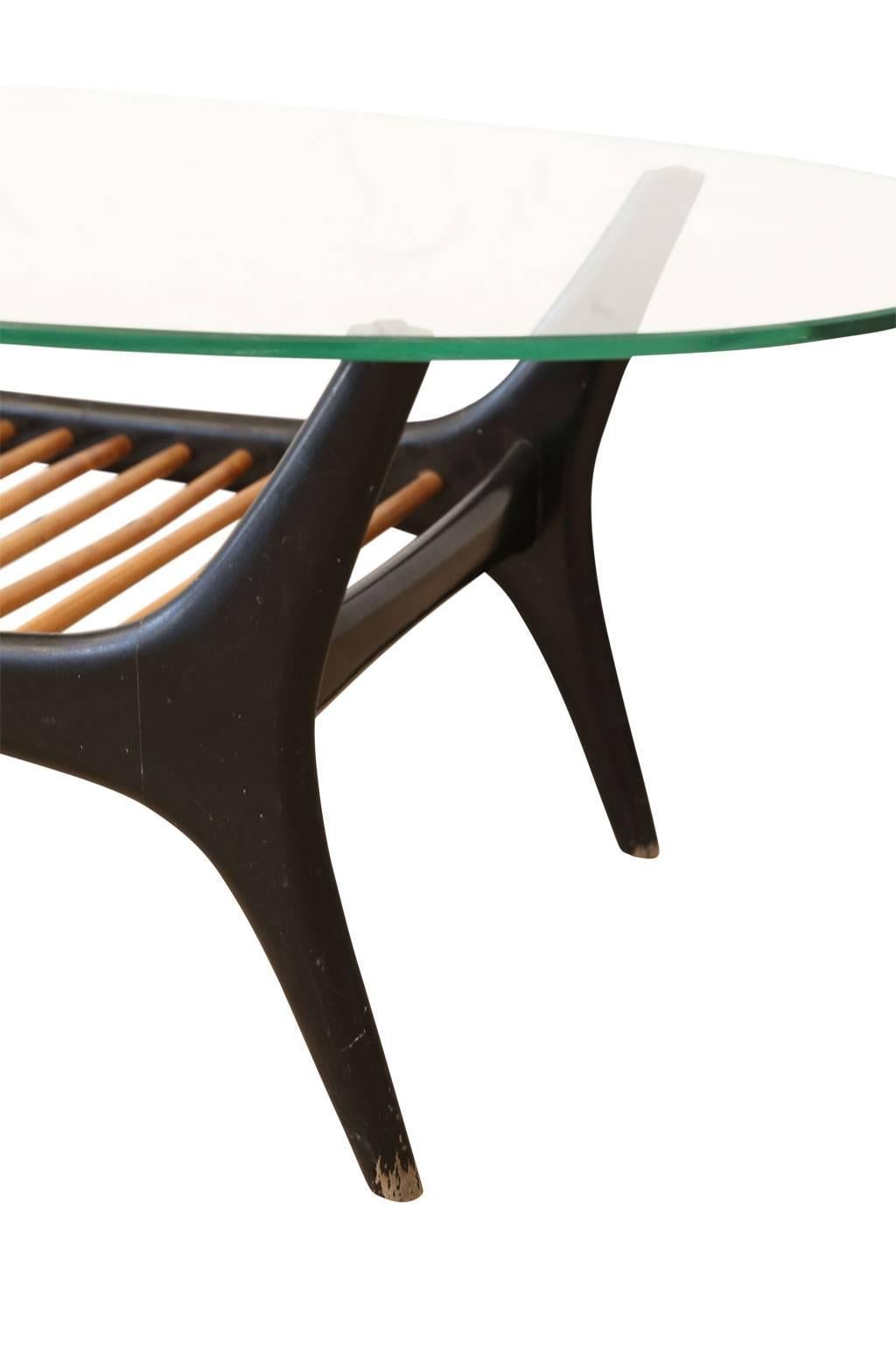 Alfred Hendrickx coffee table, designed for Belgian furniture manufacturer, Belform, in 1955. Oval glass top raised upon a black lacquered solid wood base accentuated by slender rods of light finished elm.