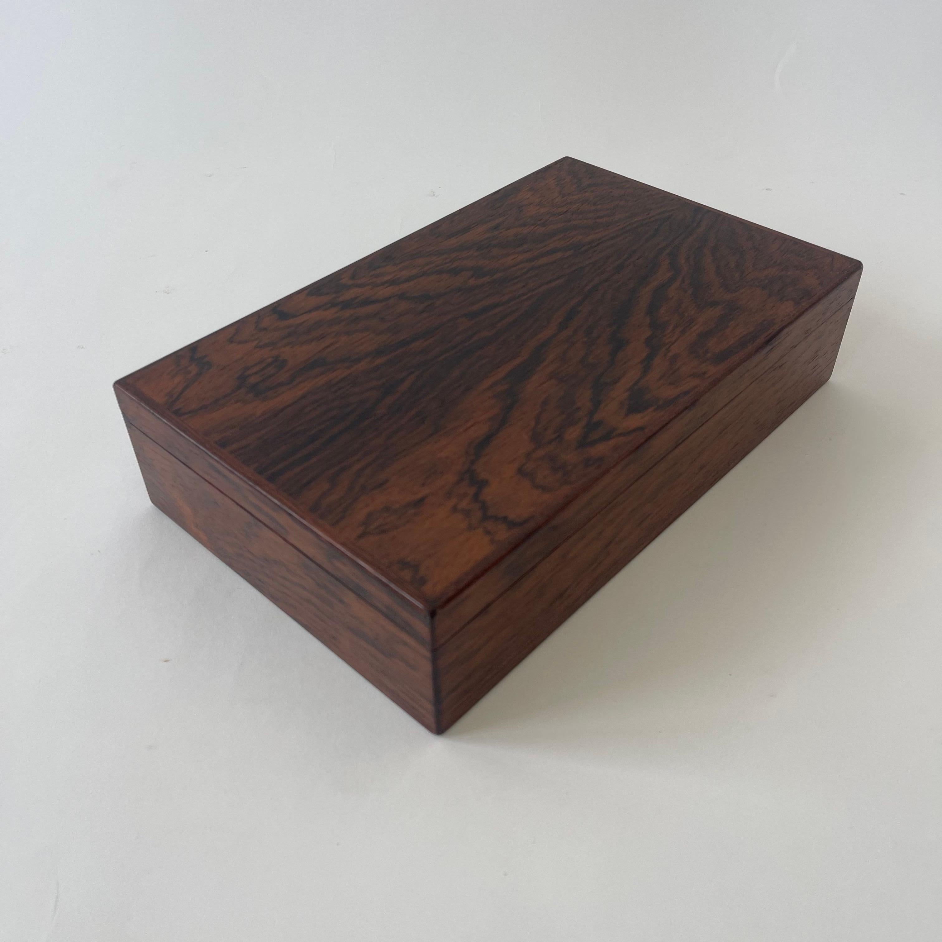 Superbe boîte à bijoux danoise moderne, réalisée en bois de rose poli et doublée de daim, avec un plateau amovible à trois sections, une section pour les bagues et trois sections inférieures.  Les séparateurs peuvent être retirés pour les bijoux de