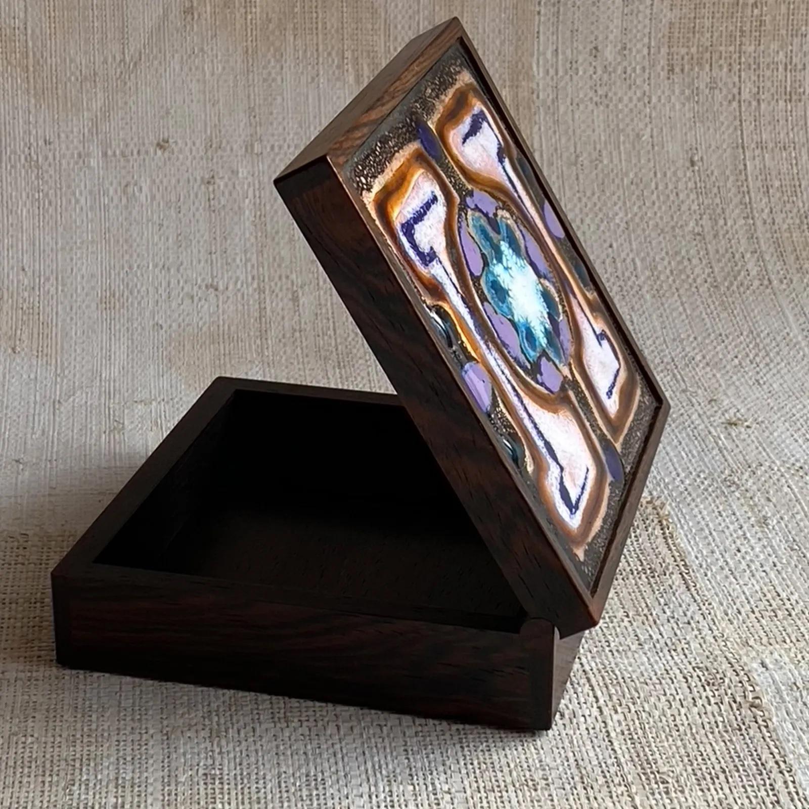 Very high quality rosewood box inset with an enamel on copper decorative panel.
Marked ‘Klitgaard’ Denmark for Alfred Klitgaard who was a postwar Danish artist whose work in enamel is now highly collectable.
11cm Square.
