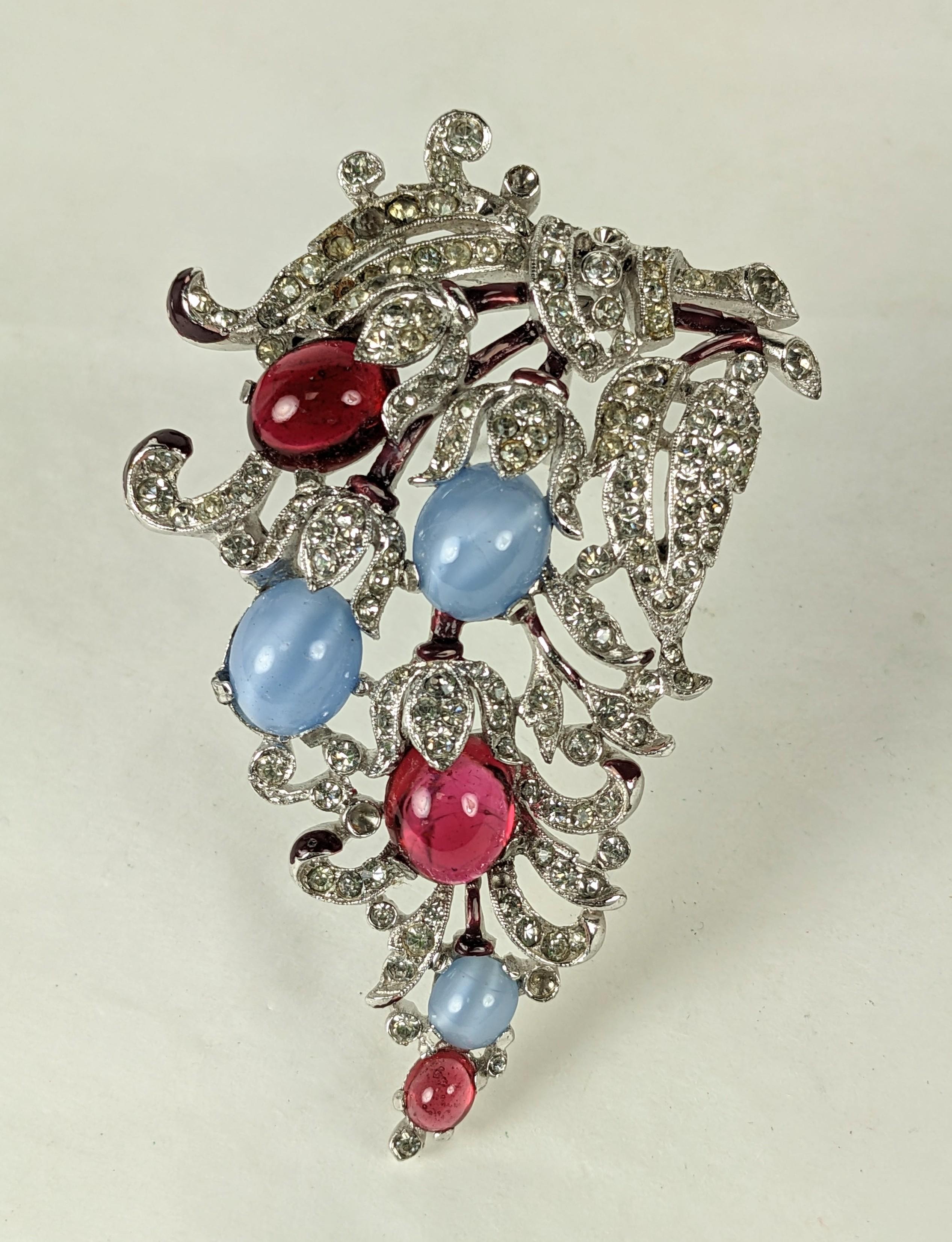 Lovley Trifari 'Alfred Philippe' blue moonstone and ruby cabochon clip brooch with dark magenta cold enamel accents and crystal pave rhinestones. Rhodium plated base metal, rhinestones, enameling, cabochons.
Marked: Trifari with Crown, Excellent