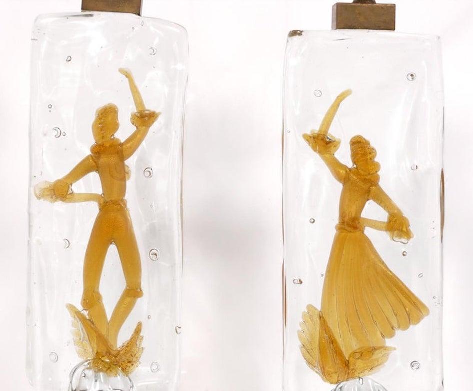 A pair of circa 1940's / 1950's hand made cased glass table lamps attributed to Alfredo Barbini for Gino Cenedese. This pair of Murano glass table lamps features a glistening gold colored figure in each of the lamps. Dancers. A man and a woman each