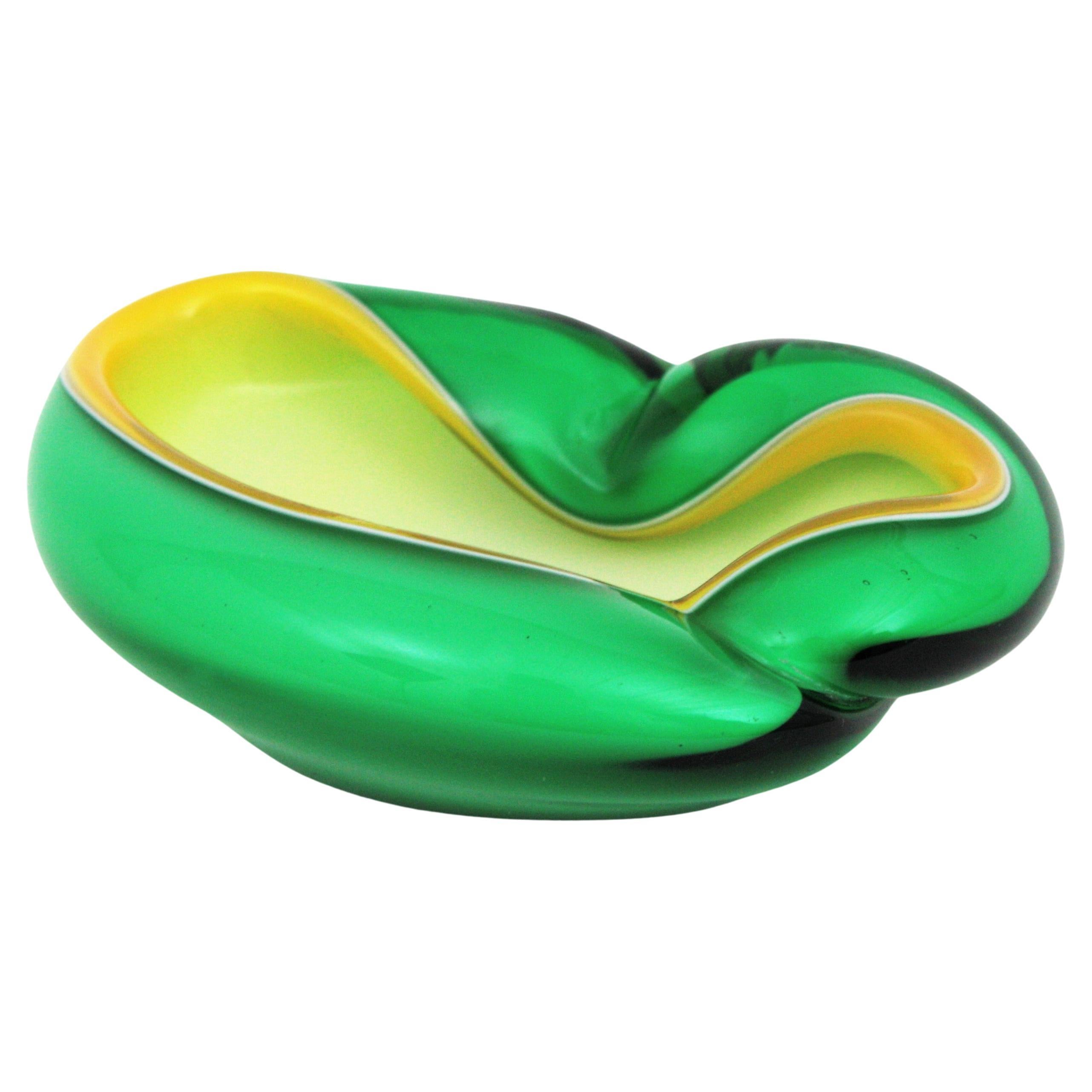 Eye-catching and colorful Murano hand blown green, yellow and white Italian art glass bowl or ashtray with folded rim. Attributed to designer Alfredo Barbini.
This asymmetric and biomorphic bowl has amazing shapes and colors using the Sommerso