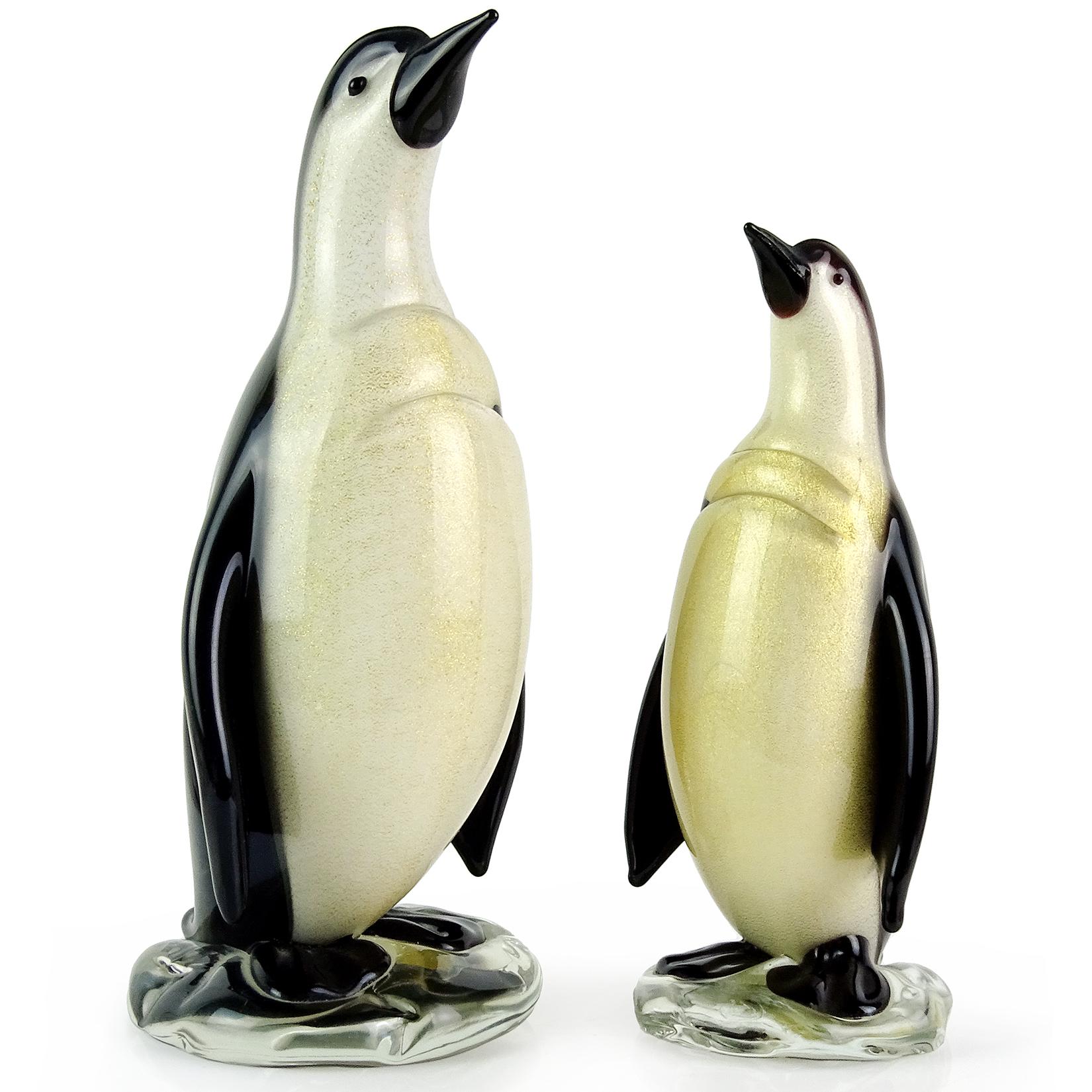 Beautiful Murano hand blown black, white and gold flecks Italian art glass penguin sculptures. Documented to designer Alfredo Barbini, with original gallery item labels. Published in his catalog as well. They are both covered in gold leaf, and stand
