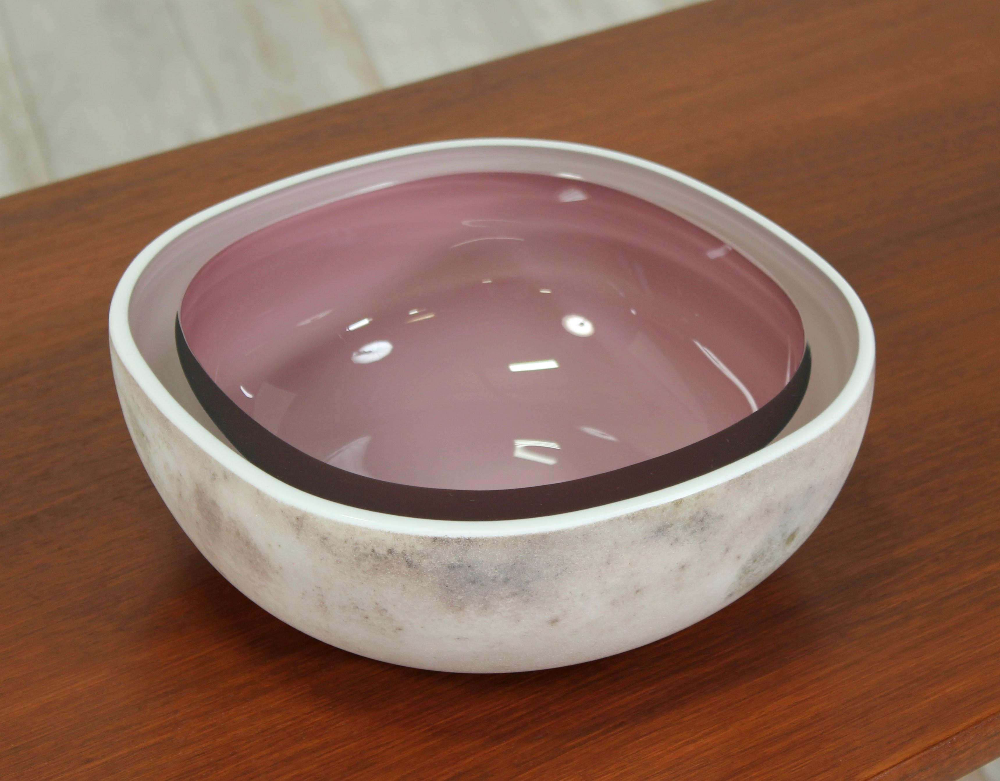      A beautiful 1960s Alfredo Barbini for Oggetti “Scavo” art glass centrepiece bowl. This piece features a textured grayish-white lava-like exterior with a polished amethyst glass interior, much like a split geode.
Etched signature: Barbini,