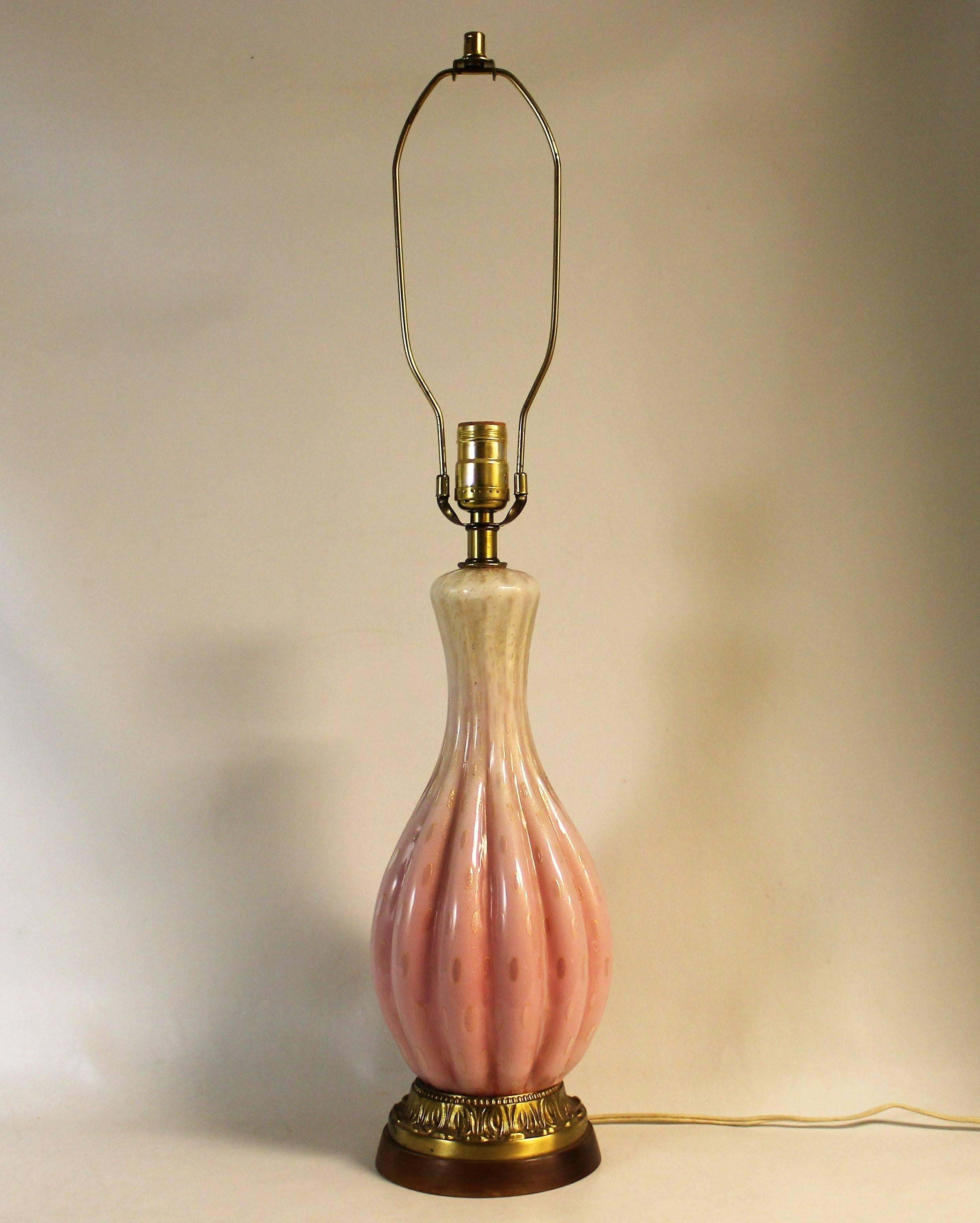 Mid-Century Modern Italian Murano glass table lamp by Alfredo Barbini. It features a ribbed Venetian pink and white body with controlled bubbles and gold flecks. It sits on a gilt bronze and wood base.

 