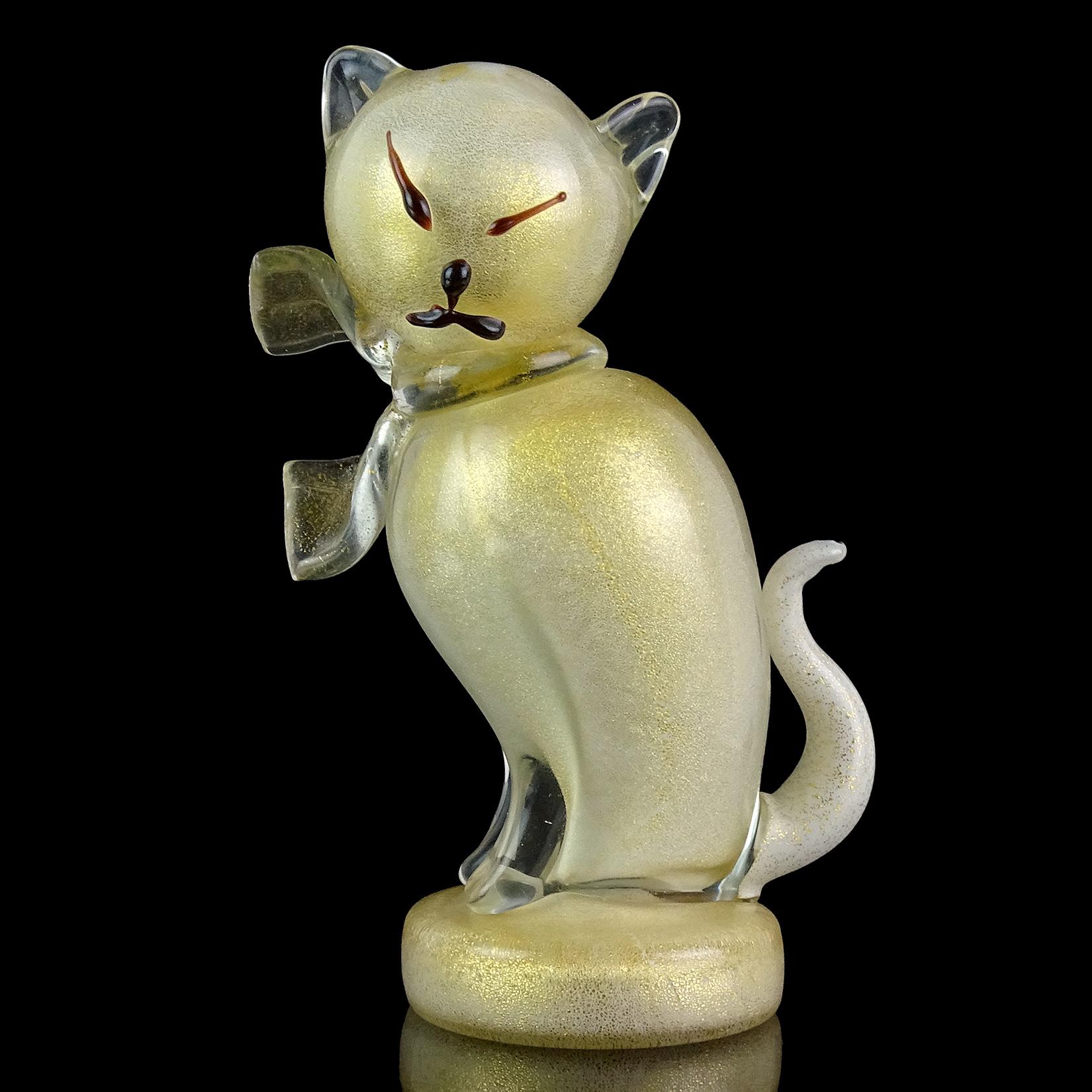 Beautiful vintage Murano hand blown white and gold flecks Italian art glass kitty cat sculpture figurine. Documented to designer Alfredo Barbini. The piece is profusely covered in gold leaf, with clear bow around its neck. Stands on a round disk,