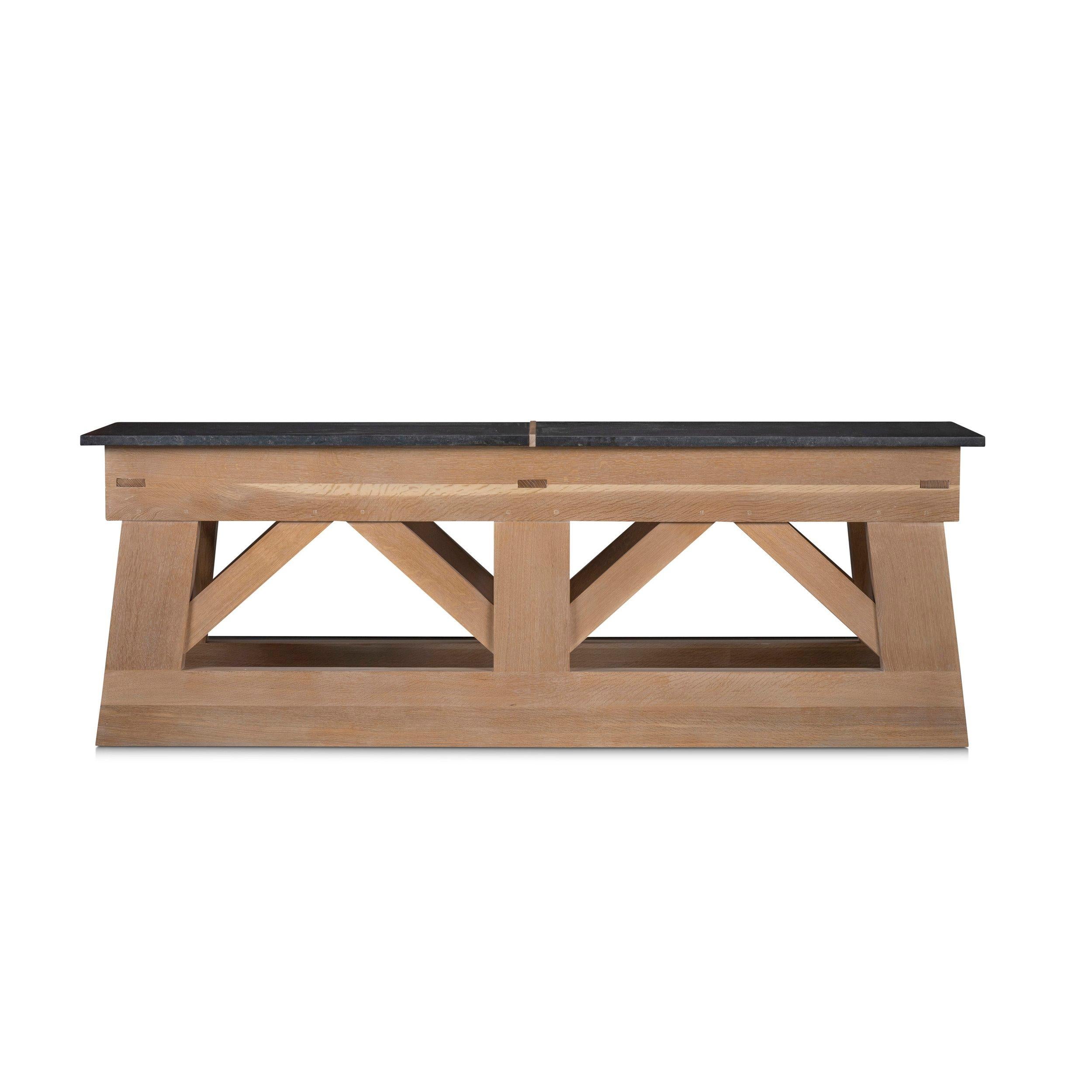 A monumental architectural console based on a nineteenth-century French foundry workbench. The massive oak timbers and two-piece stone slab top convey a sense of strength and permanence.

- Oak Solids
- As Shown in Avena Finish with Negresco Stone