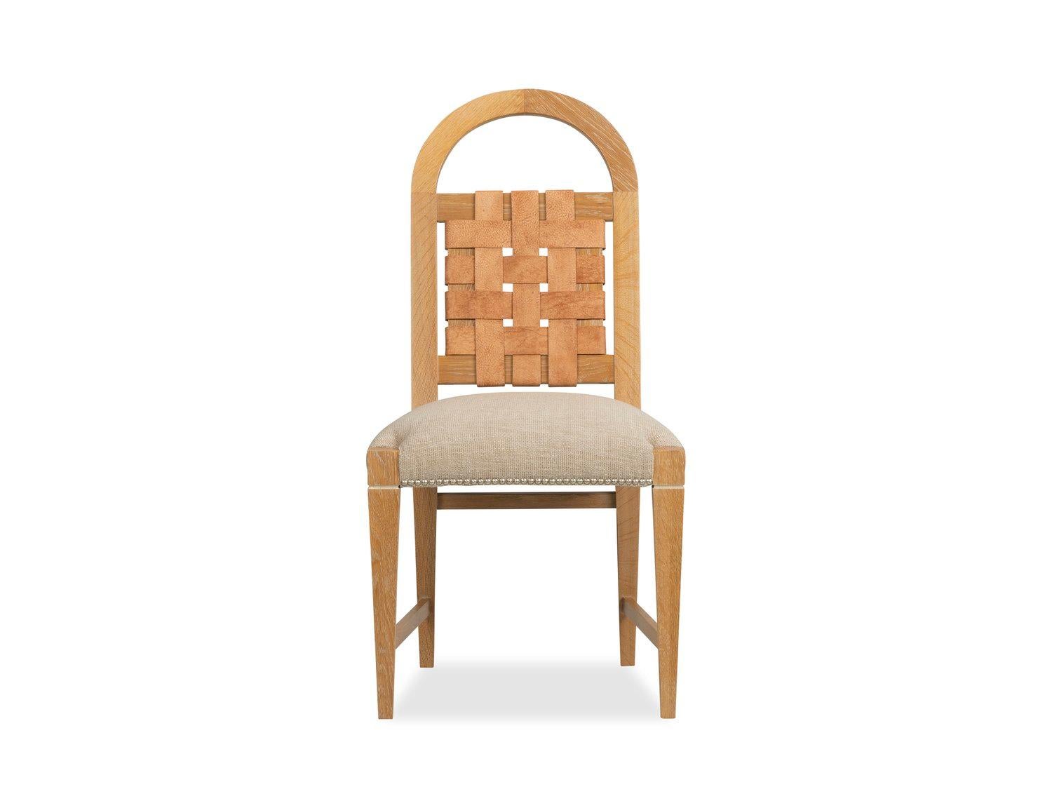 The distinctive arched back of this supremely comfortable dining chair provides a convenient handle to move the chair, and frames a panel of woven suede belting leather making a bold focal point. Hand-applied nailheads, a traditional upholstered