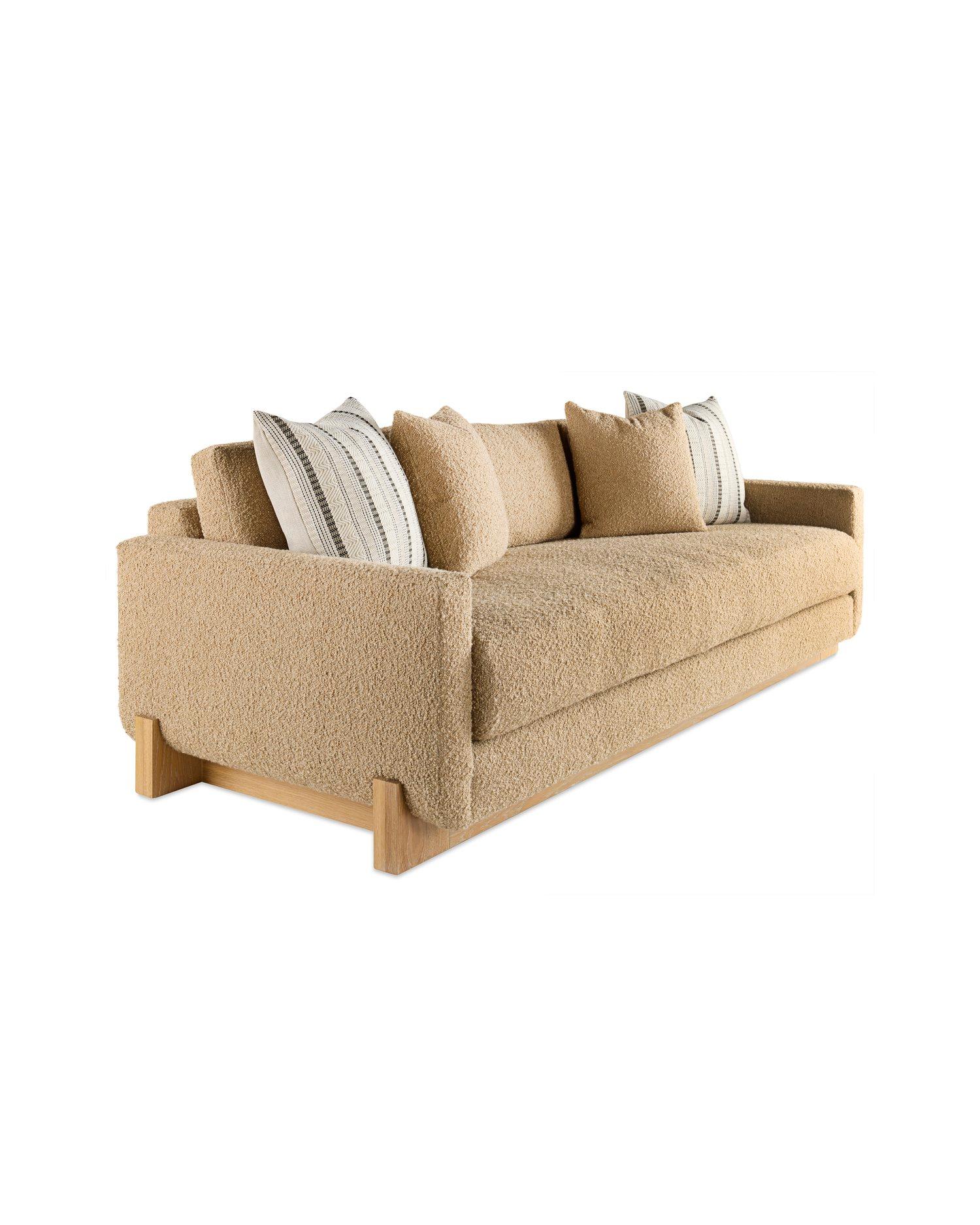 A unique sofa form of radiused planes resting on a wood sled base. The sleek modern shape has a bench seat and loose back cushions; the wood elements give a custom appearance.