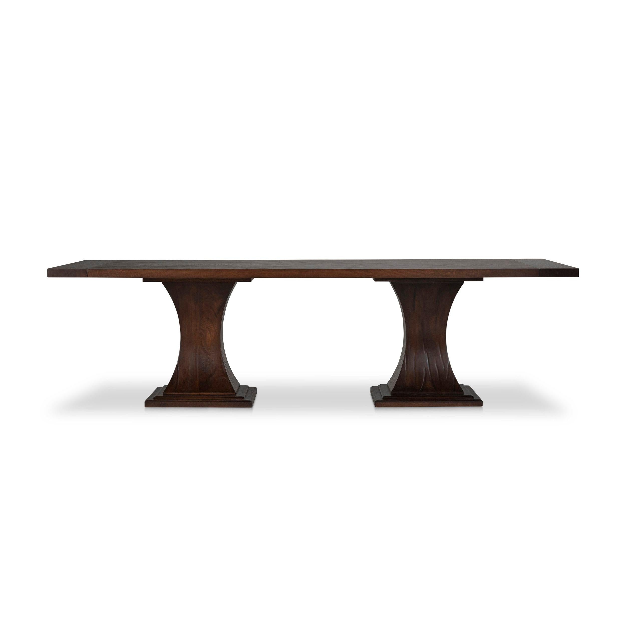Casual yet elegant, this rectangular dining table has a hand scythed plank top supported by a pair of coved block bases that allow generous legroom for guests. The rustic oak finish and exposed iron bolt heads give the piece a relaxed feel. Finished