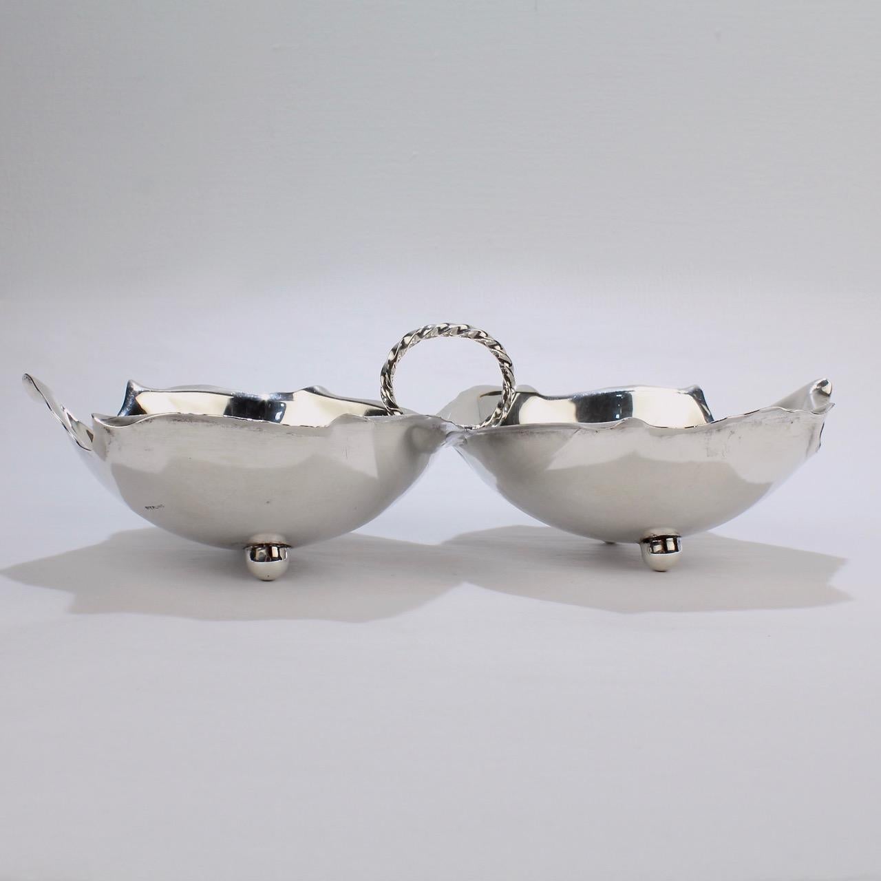 A terrific Alfredo Sciarrotta two-lobed sterling silver bowl.

Each side in the form of a leaf, with button feet, and joined by a wire twist handle.

Simply perfect for table top!

The base is marked Sterling, Handmade by Sciarrotta, the Bailey,