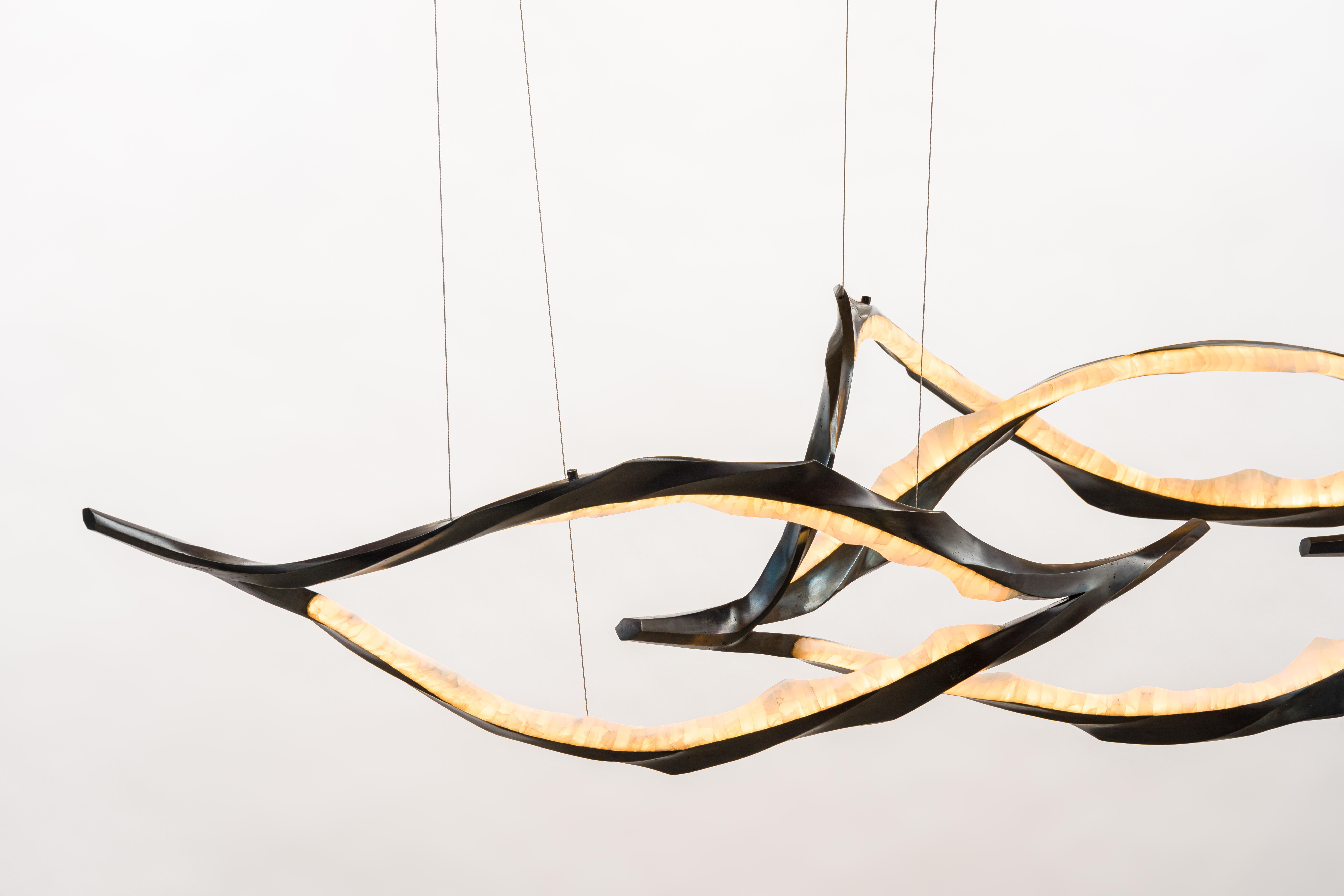 Composed of a series of tiered, interconnected bronze and onyx ribbons, Markus Haase’s new series of lighting, the Algae Series, creates a sweeping landscape of radiant, sculpted light. Combining a mastery of traditional sculpting techniques with a