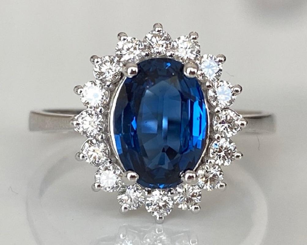 Offered in new condition,18 kt  ring in white gold, with an oval cut sapphire (beautiful colour) of 1.65 ct. The sapphire is surrounded by an entourage of 16 brilliant cut diamonds, approx. 0.48 ct in total, quality E/F/VVS/VS. ALGT certificate is