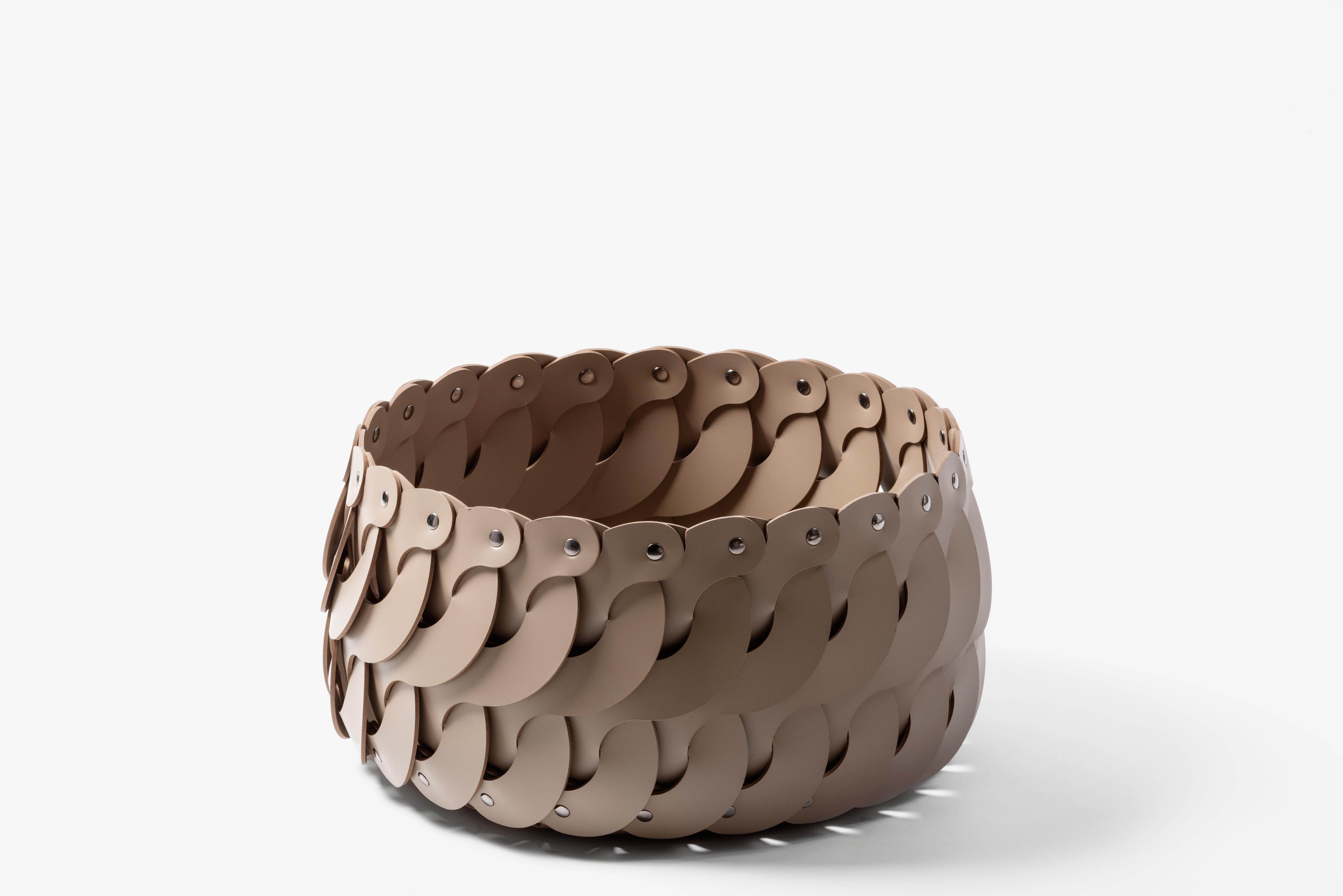 This elegant round basket with lid features a unique woven frame handcrafted of S-shaped taupe leather strips. Perfect to store any home essentials, it can also be used outdoors on a patio or poolside.

It is available in the Alicante colors and