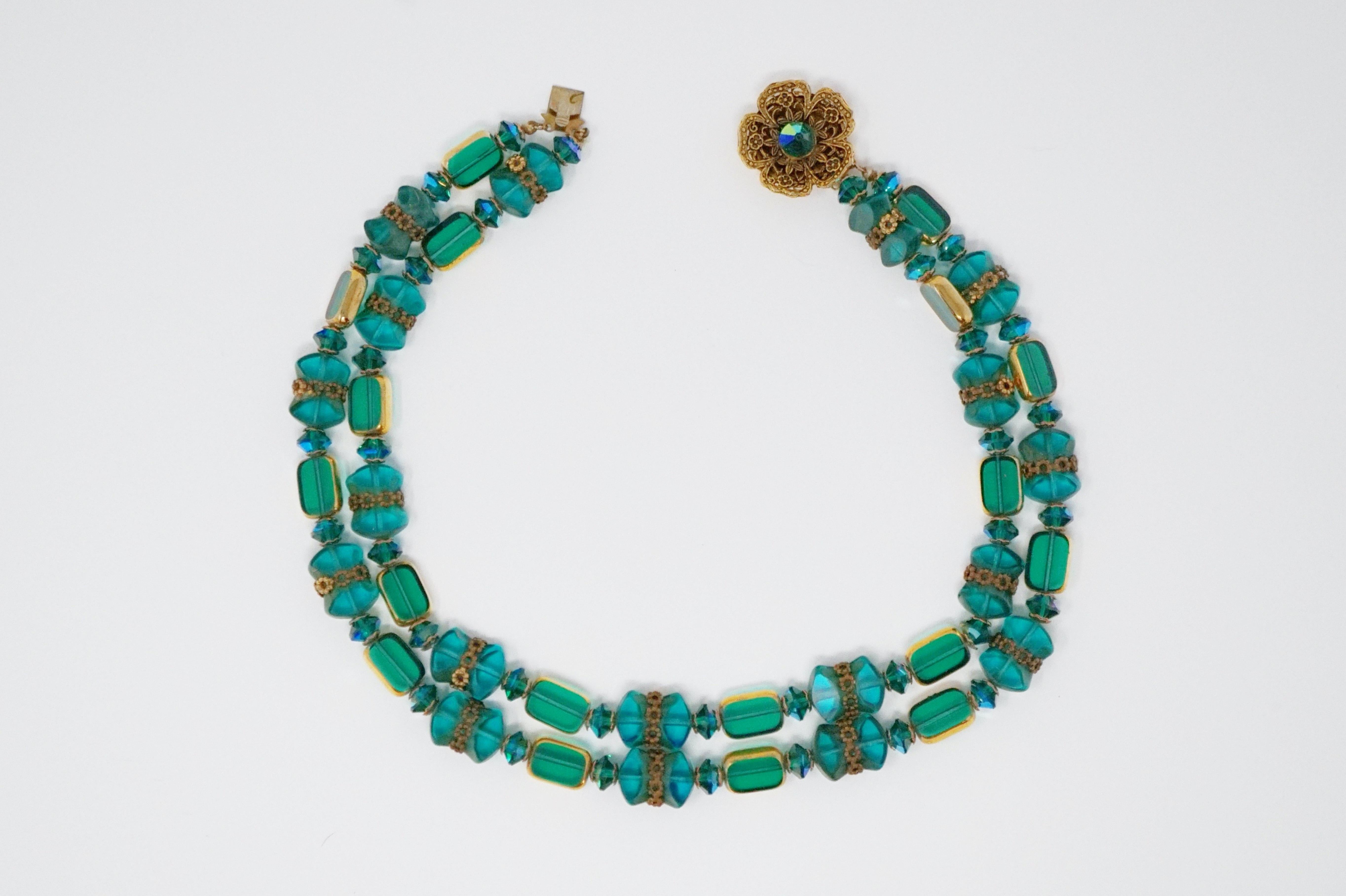 This striking Alice Caviness beaded necklace is made from the most gorgeous shade of peacock green glass and crystal beads with gilded accents and a beautiful flower box clasp that can be worn at the front or back of the necklace. This is a