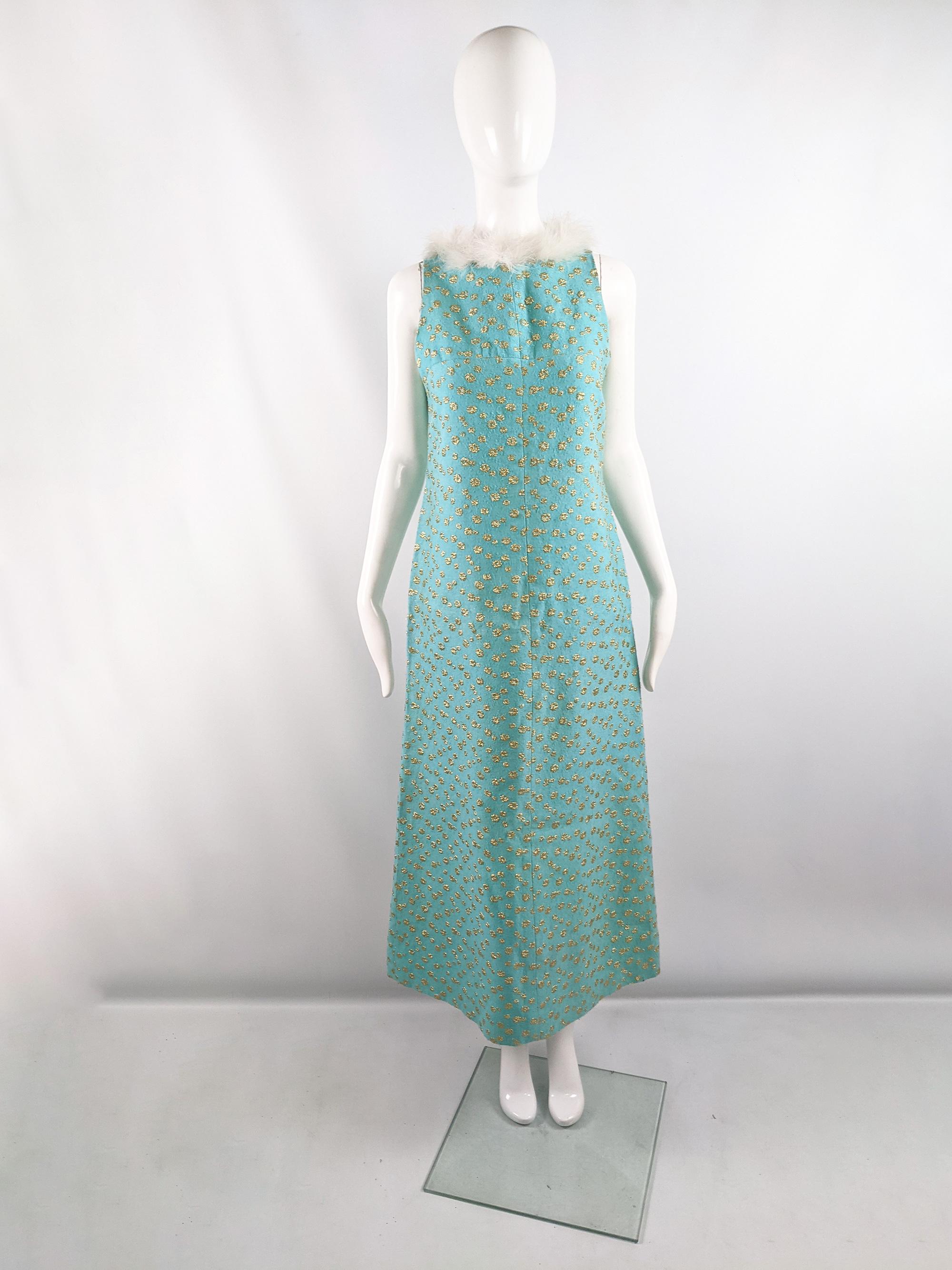 A glamorous vintage maxi sleeveless evening / party dress from the 60s by quality British fashion designer, Alice Edwards. In a turquoise and gold brocade fabric with a white feather trim. In a column / long A-line shape that gives a glamorous mod