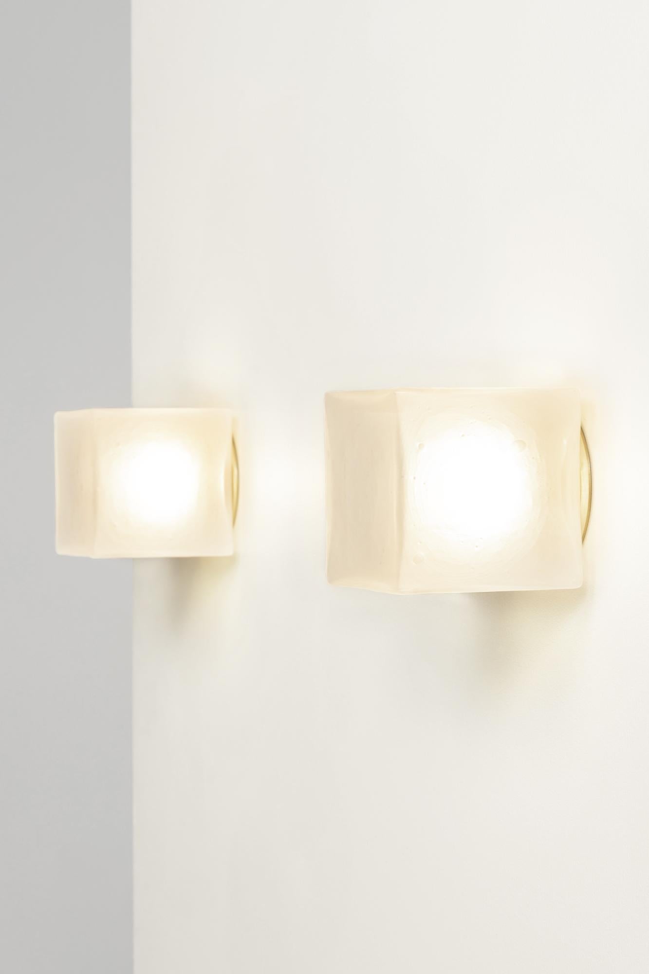 The Alice collection is inspired by brutalist modular architecture. The textured hand blown glass cubes are sandblasted to create a soft glow. Available in satin brass or matte black, and as a ceiling flush mount.

5 in (13 cm) W x 5 1/4 in (13.5