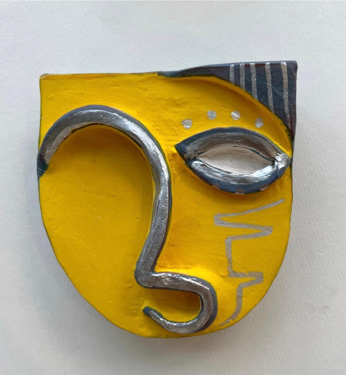 Clay sculpture of a mask, with the outline of the eyes, mouth and hair painted in yellow, silver and gray. 

Unique one of a kind painting signed by the artist. 

ARTIST BIO 
Alice Mizrachi is a New York based interdisciplinary artist and educator