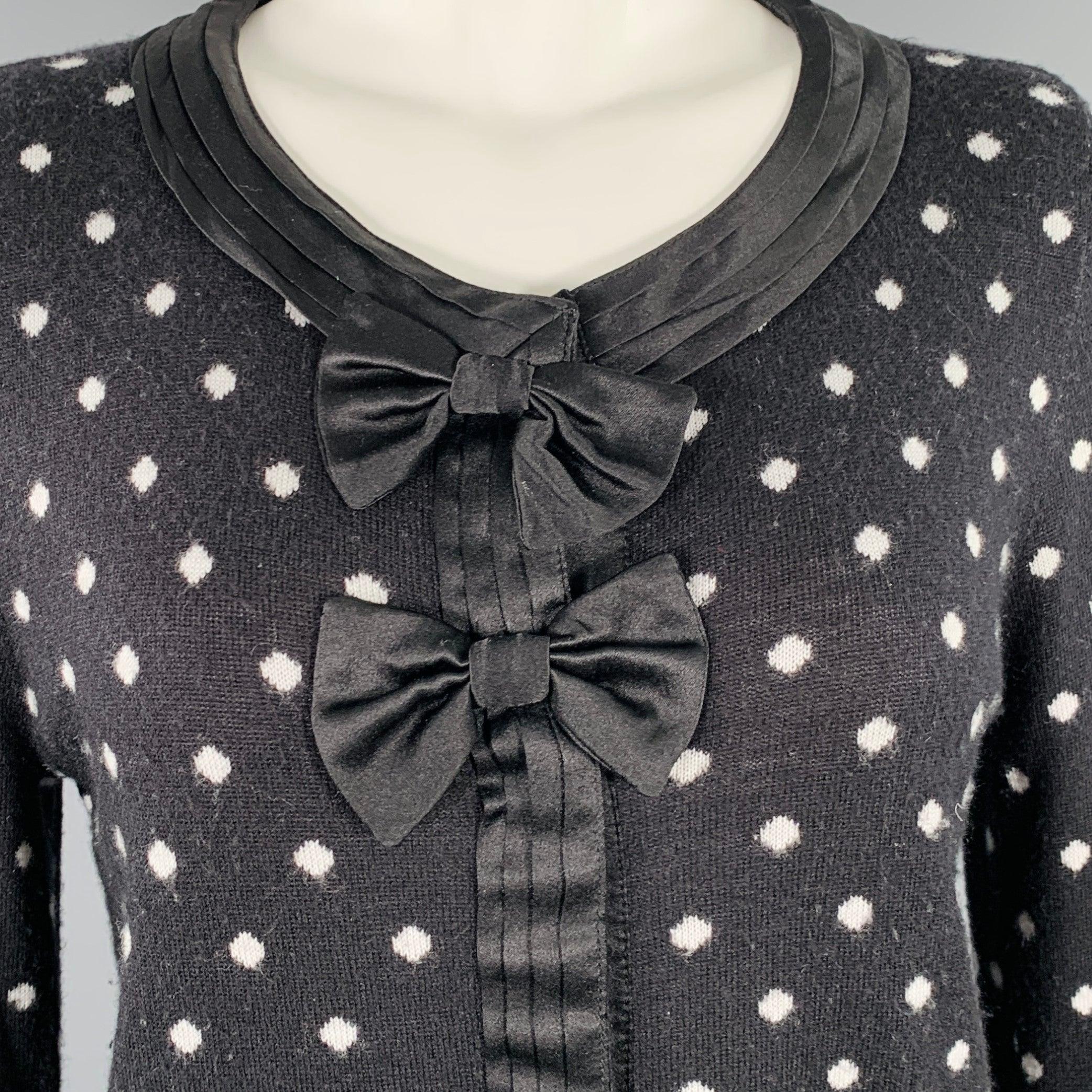 ALICE + OLIVIA cardigan
in a black and white rayon blend knit featuring a polka dot pattern, pleated trim, and hidden snap closure with double bow accent.Very Good Pre-Owned Condition. Minor pilling throughout. 

Marked:   M 

Measurements: 
