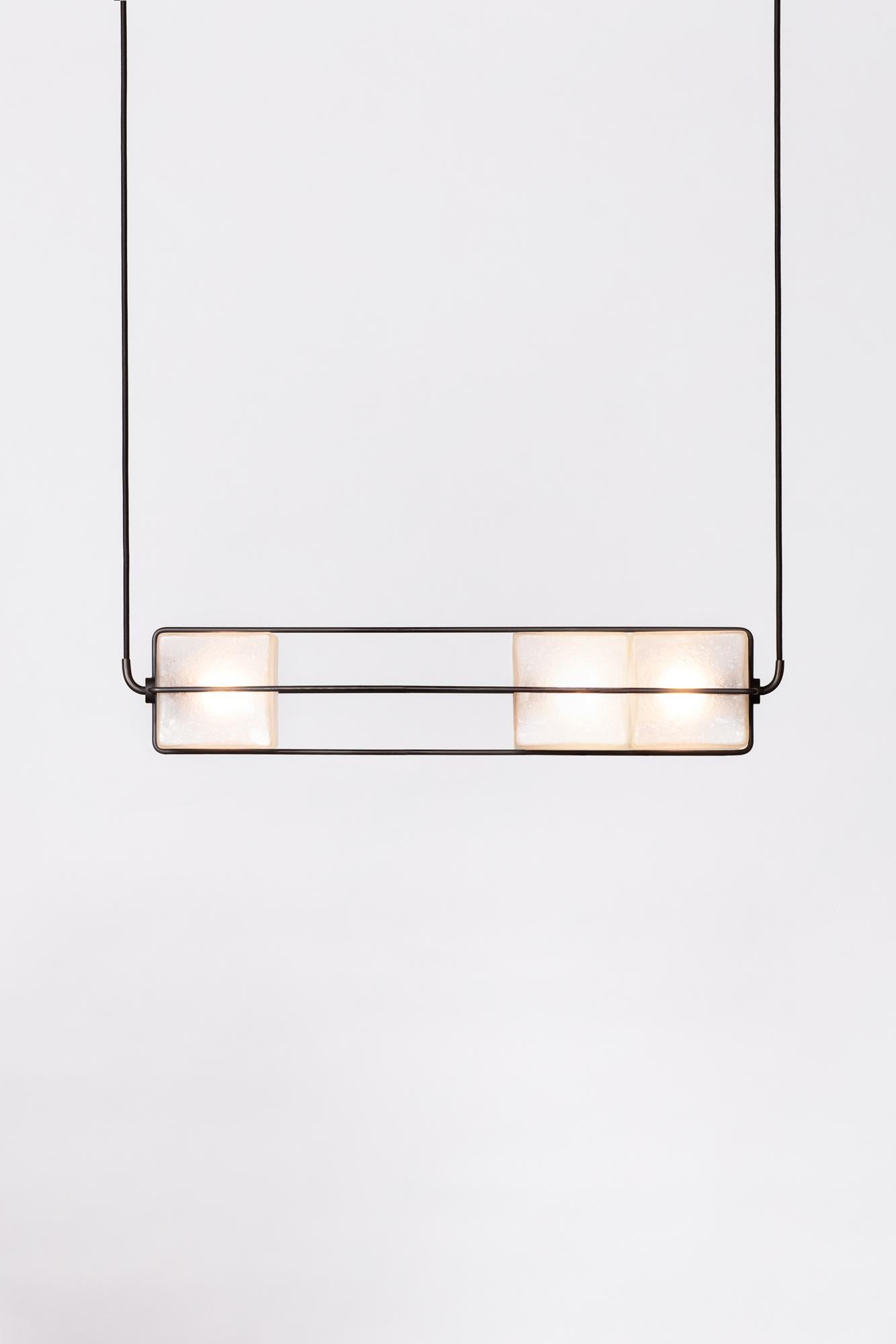 The Alice collection is inspired by brutalist modular architecture. The textured hand blown glass cubes are sandblasted to create a soft glow and stacked together to diffuse light in different intensities. The frame is made of solid brass, finished