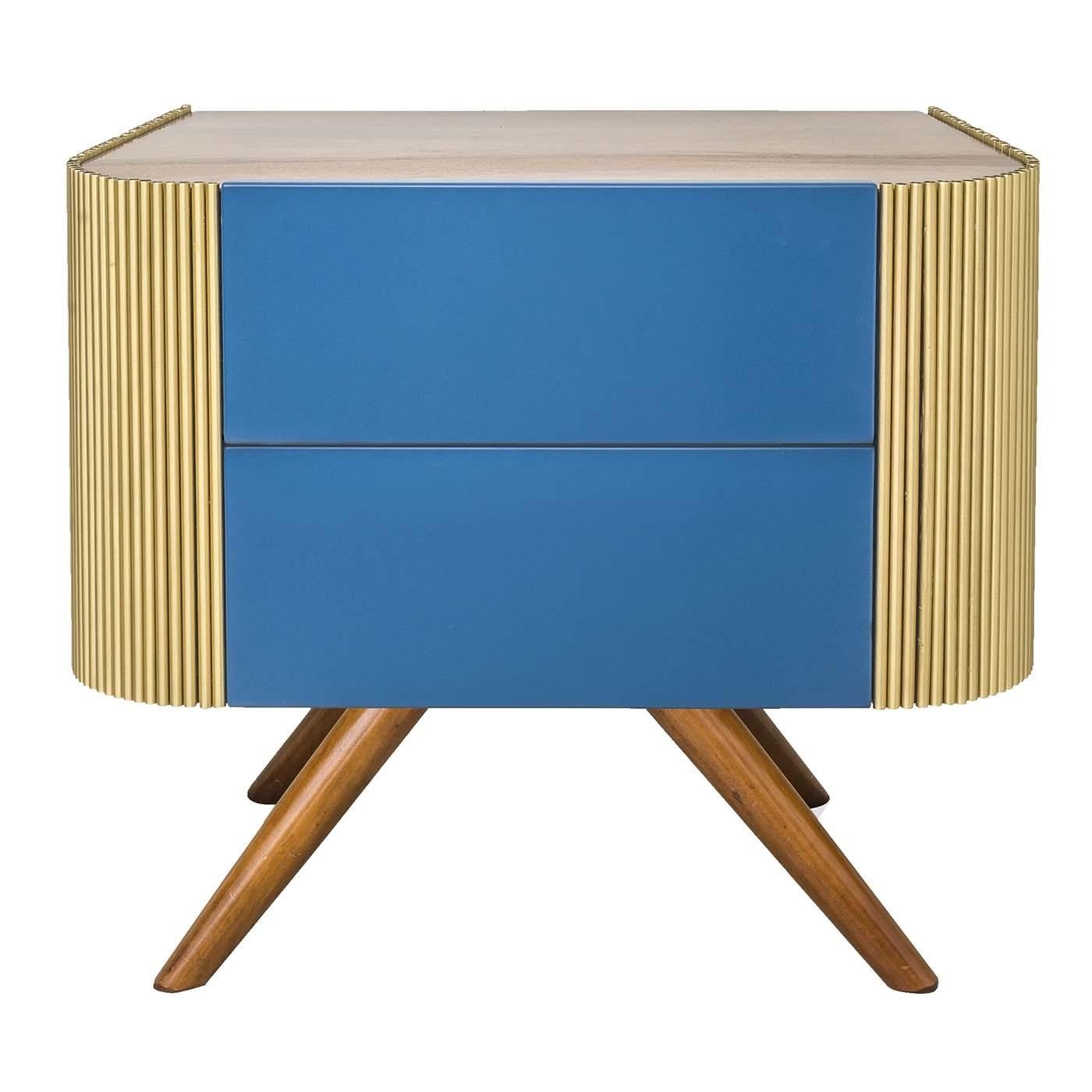 This nightstand with a bit of a retro feel will be sure to liven up any bedroom space. This piece has a walnut wood structure and boasts two bright blue drawers to tuck away objects. Contrasting beveled sides covered in thin brass rods and dark