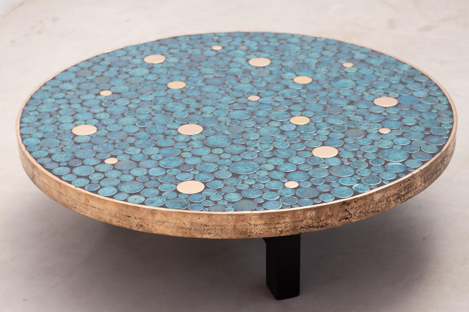 Contemporary coffee table by Belgian artist ALIETTE VLIERS.
This table features a tablet with plenty of unique ceramic circle pieces with different sizes, offering a range of shades of blue combined with brass circle pieces. The whole is framed by a