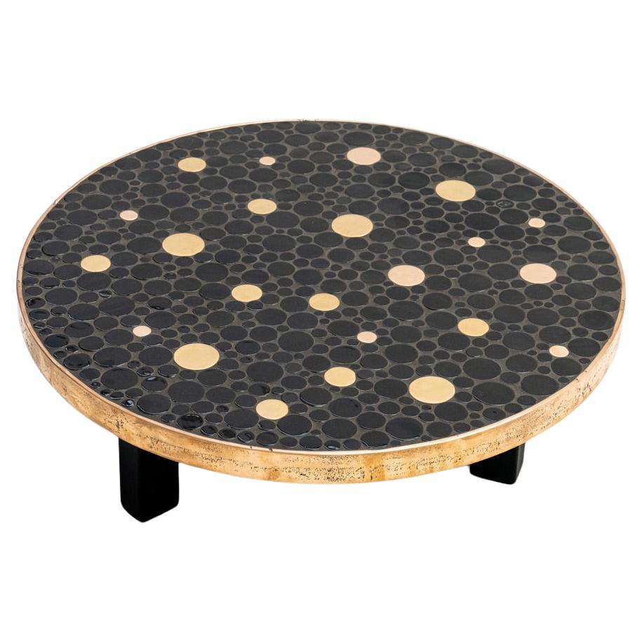 Contemporary coffee table by Belgian artist ALIETTE VLIERS.

This table features a tablet with plenty of unique ceramic circle pieces with different sizes combined with brass circle pieces. The whole is framed by a bronze hoop. The tabletop rests