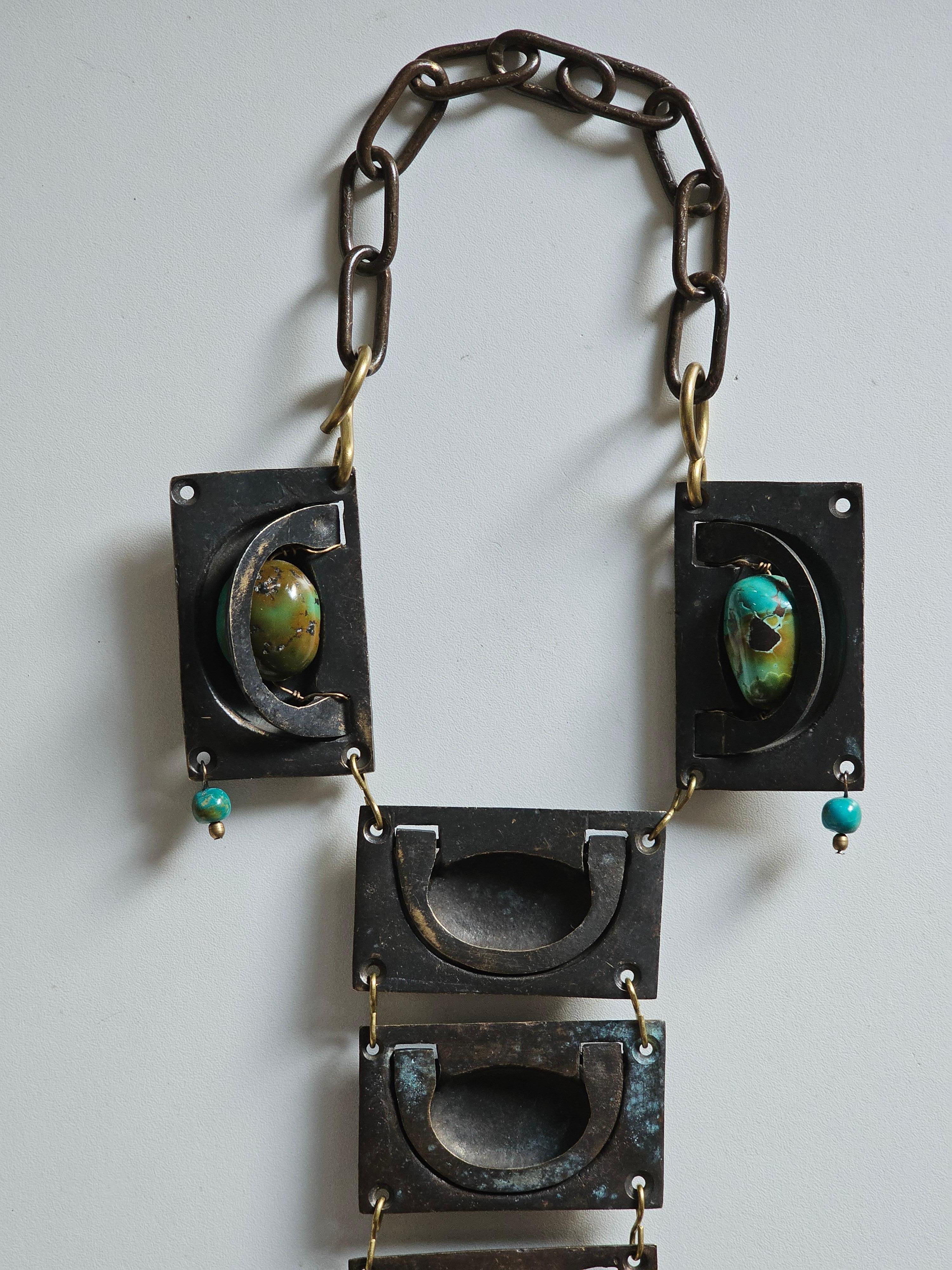 Collana Statement Secret Drawers composta da 9 cassetti con maniglia in ottone patinato nero e naturale dell'inizio del XX secolo, 2 grandi turchesi africani lucidi, 2 piccole perle turchesi e catena in ottone

Unico 

Dimensioni 
cm: L 18 x L 47 x