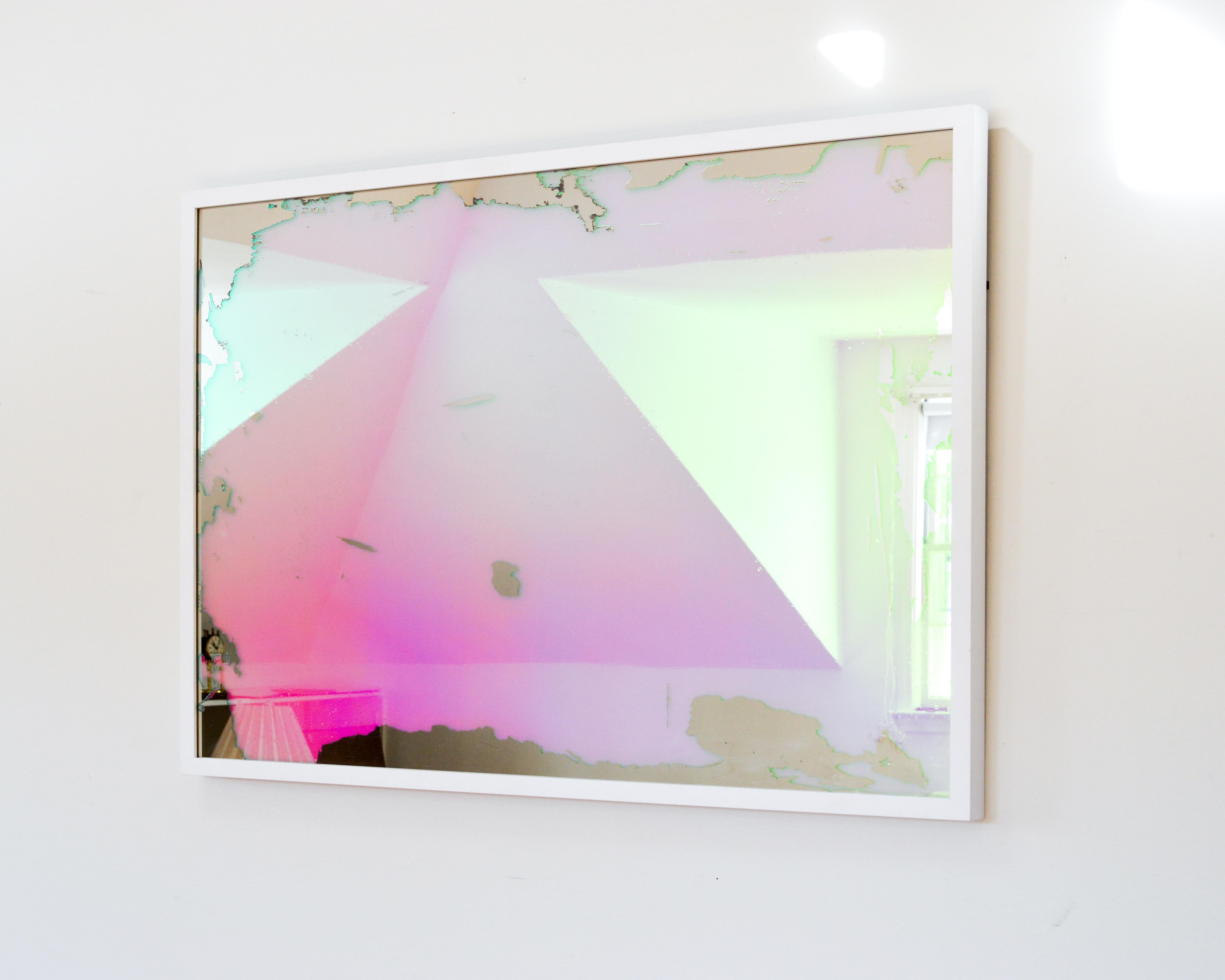 This contemporary piece is made with dichroic film on mirror and is framed in a modern white frame. The application of the film creates a changing colorful aesthetic so that the viewer sees different colors as they change the angle at which they