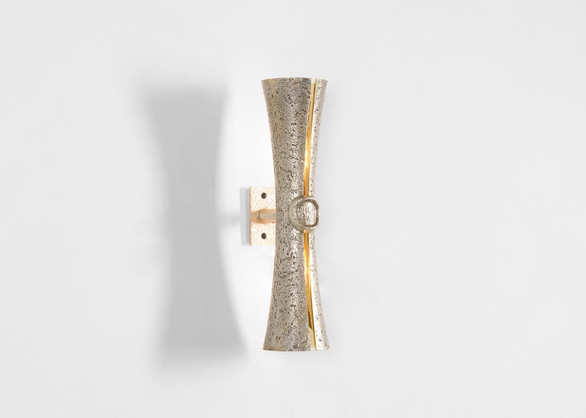 Cinched at the waist and split delicately along its length to reveal a polished bronze interior and, when i
illuminated, a ribbon of light, this shapely wall lamp reads as a graceful reinterpretation of the sconce. Designed to add a touch of