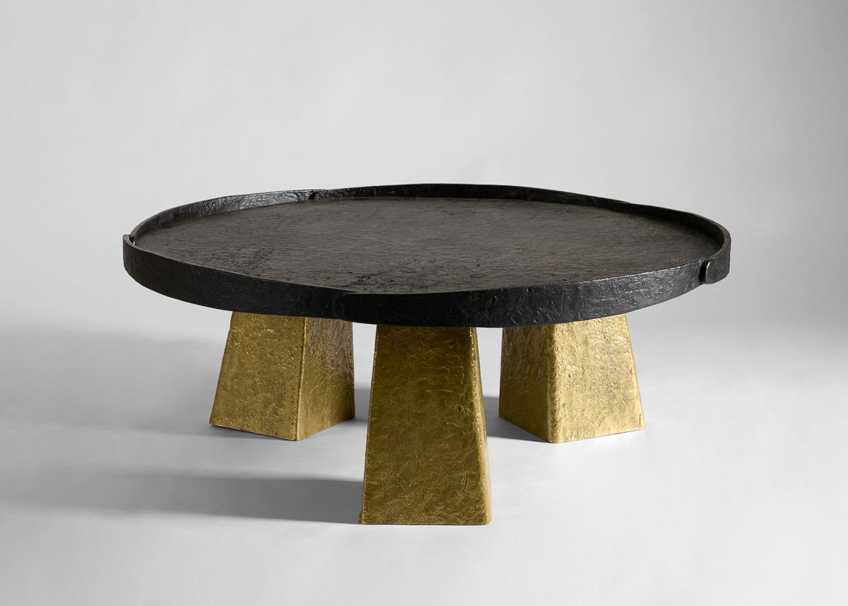 With its monumental legs supporting an equally dominating tabletop, this table’s forms and materiality hearken back to a time when the elemental reigned. The generously sized tabletop, with its dappled texture, while the table’s shape and