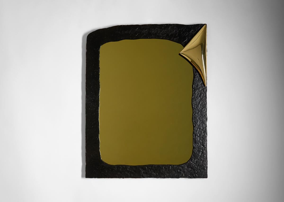 Avec sa forme rectangulaire irrégulière composée de bronze noirci grossièrement taillé et son angle poli parfaitement rectiligne (comme si l'ensemble avait été trempé timidement par le haut), ce miroir exquis établit un équilibre entre deux