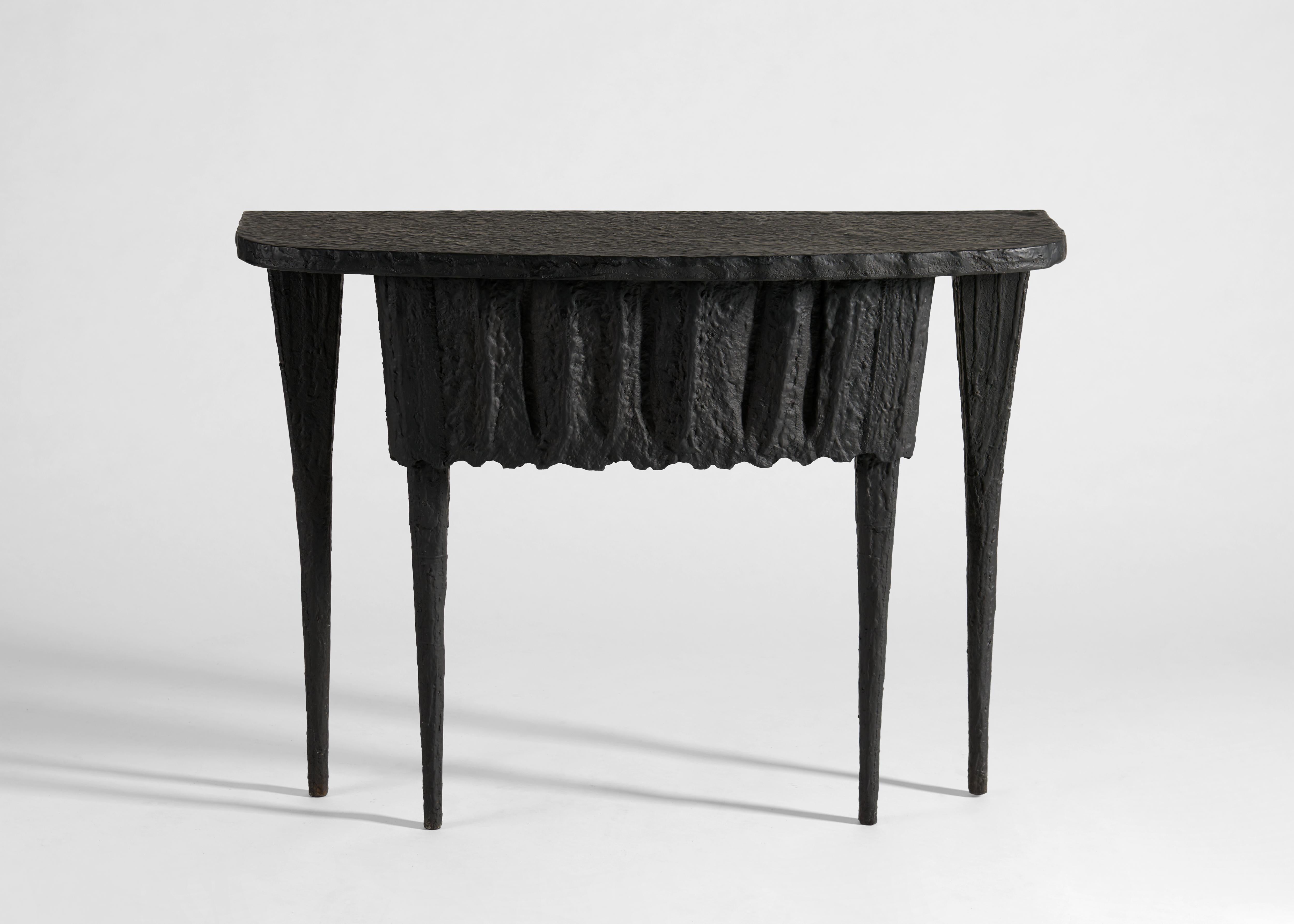 With no two parallel sides, Shivini stands out as a statement piece. The console's tapered legs and organic texture evoke the natural grandeur of stalactites formed over thousands of years. Its regular shape is accented by a patinated bronze finish