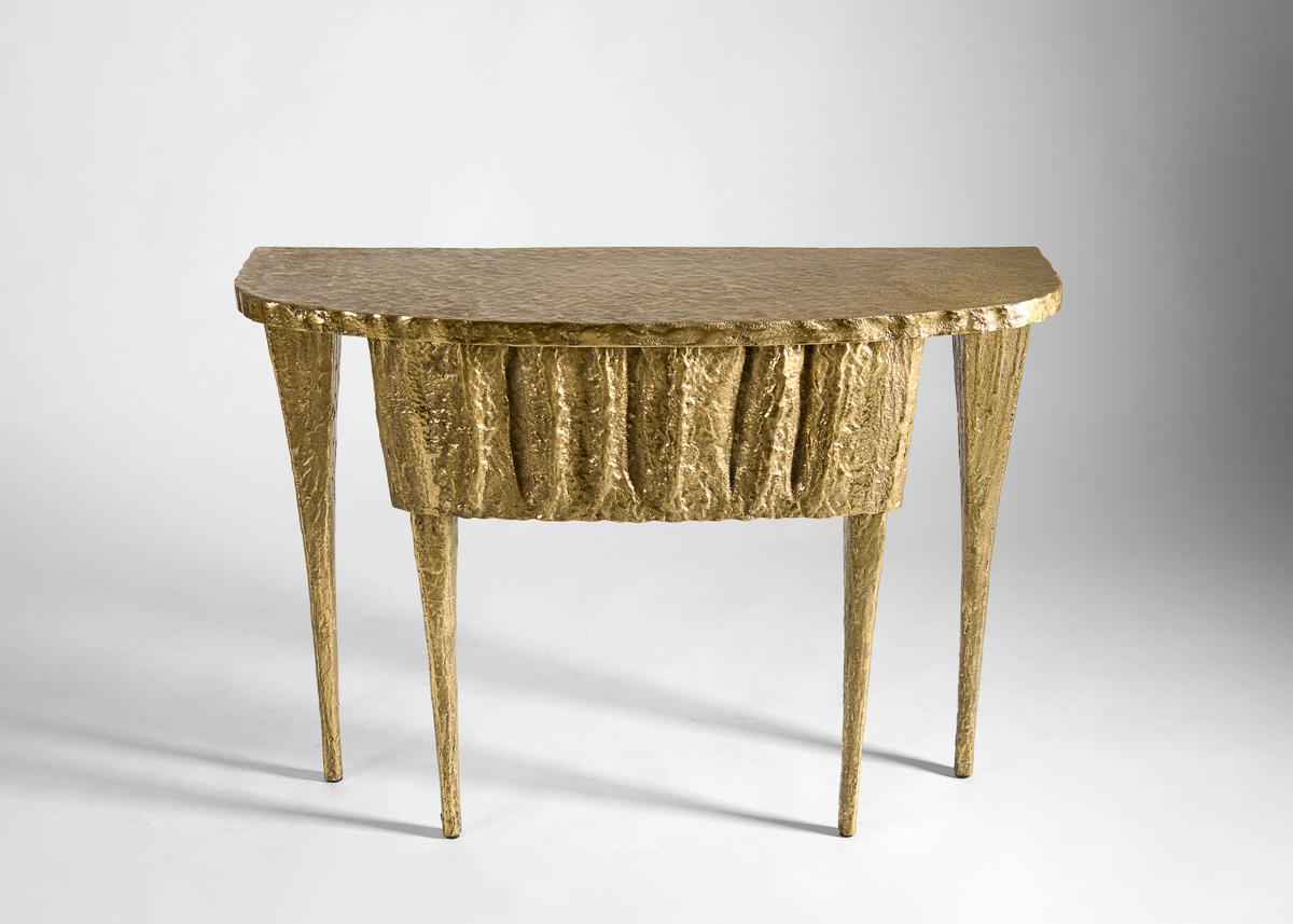 With no two parallel sides, Shivini stands out as a statement piece. The console's tapered legs and organic texture evoke the natural grandeur of stalactites formed over thousands of years. Its regular shape is accented by a patinated bronze finish