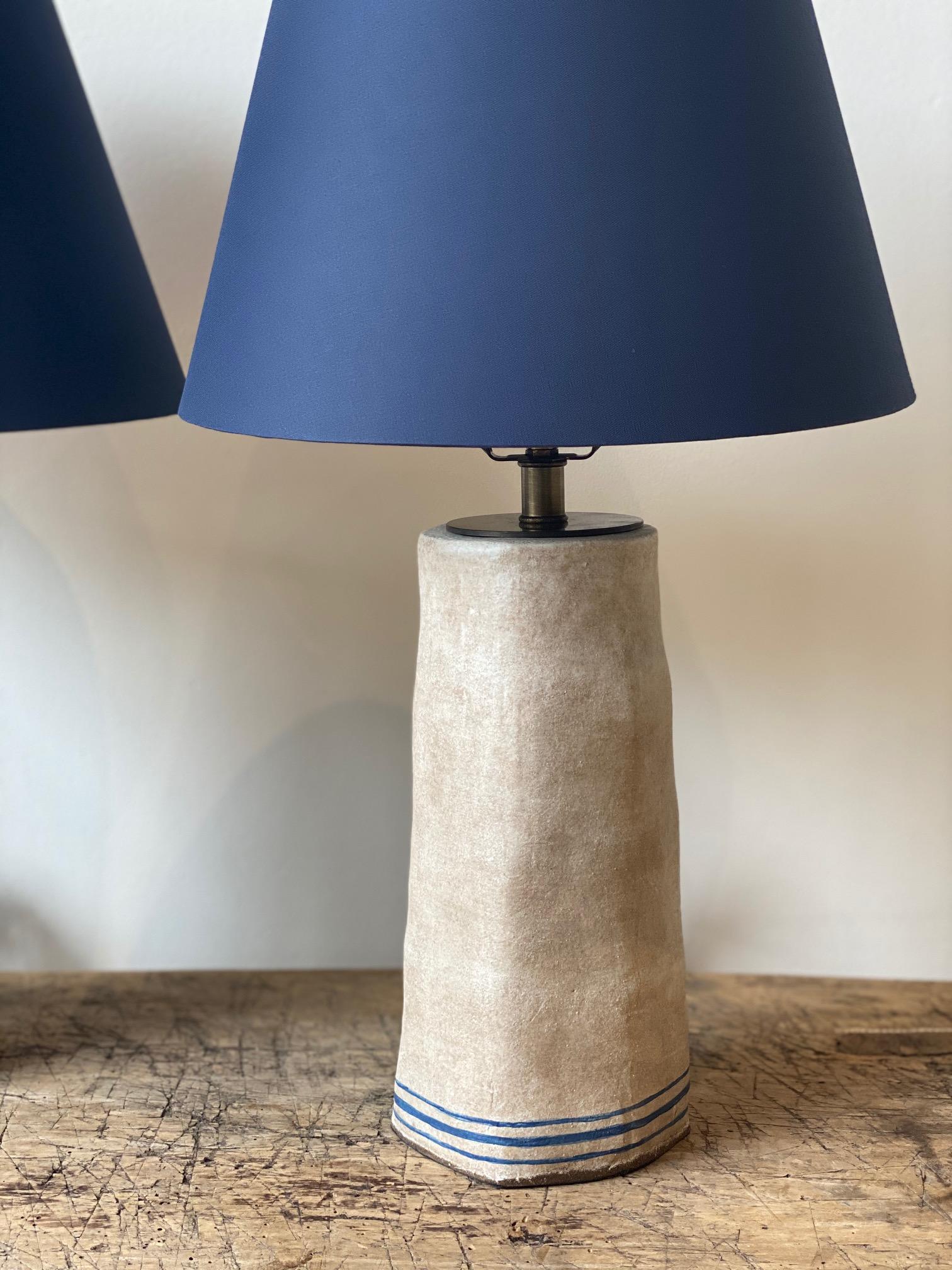 Handmade lamp bases by the French American artist Alix Soubiran. The lamps come with brown twist cord. Sold as a pair, navy custom bookcloth shade included.

The lamp base measures 11