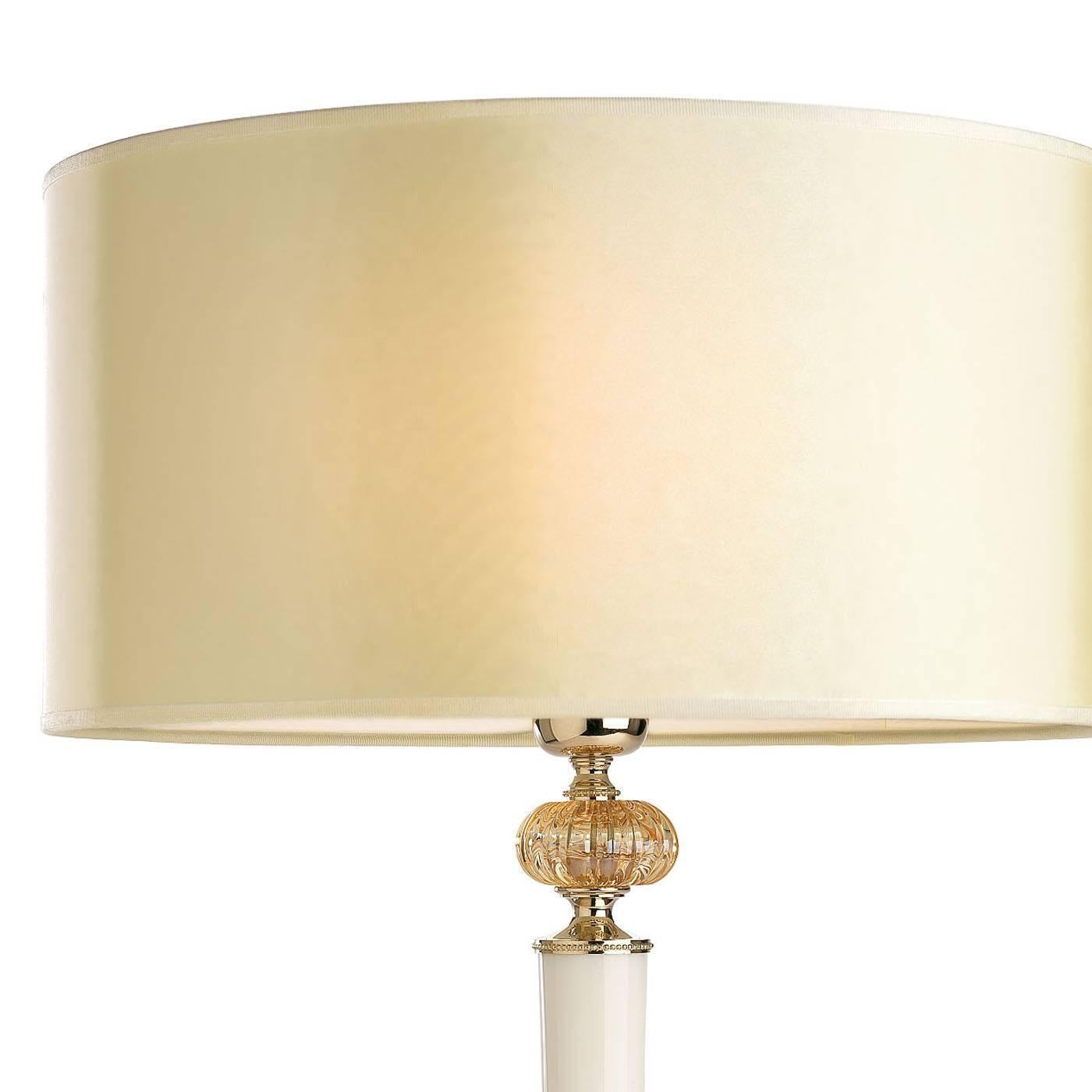 This exquisite desk lamp features an ornate round base in brass with a light gold finish supporting an elegant shaft in Calacatta marble that is adorned at the top with a crystal decoration. The delicate hue of the fabric covering the shade is in