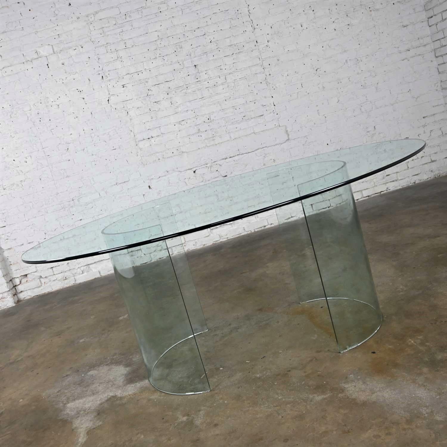 Stunning all glass modern dining table with dual (2) semi-circle pedestal bases and an elliptical shaped oval top. Beautiful condition, keeping in mind that this is vintage and not new so will have signs of use and wear. There is a chip on the