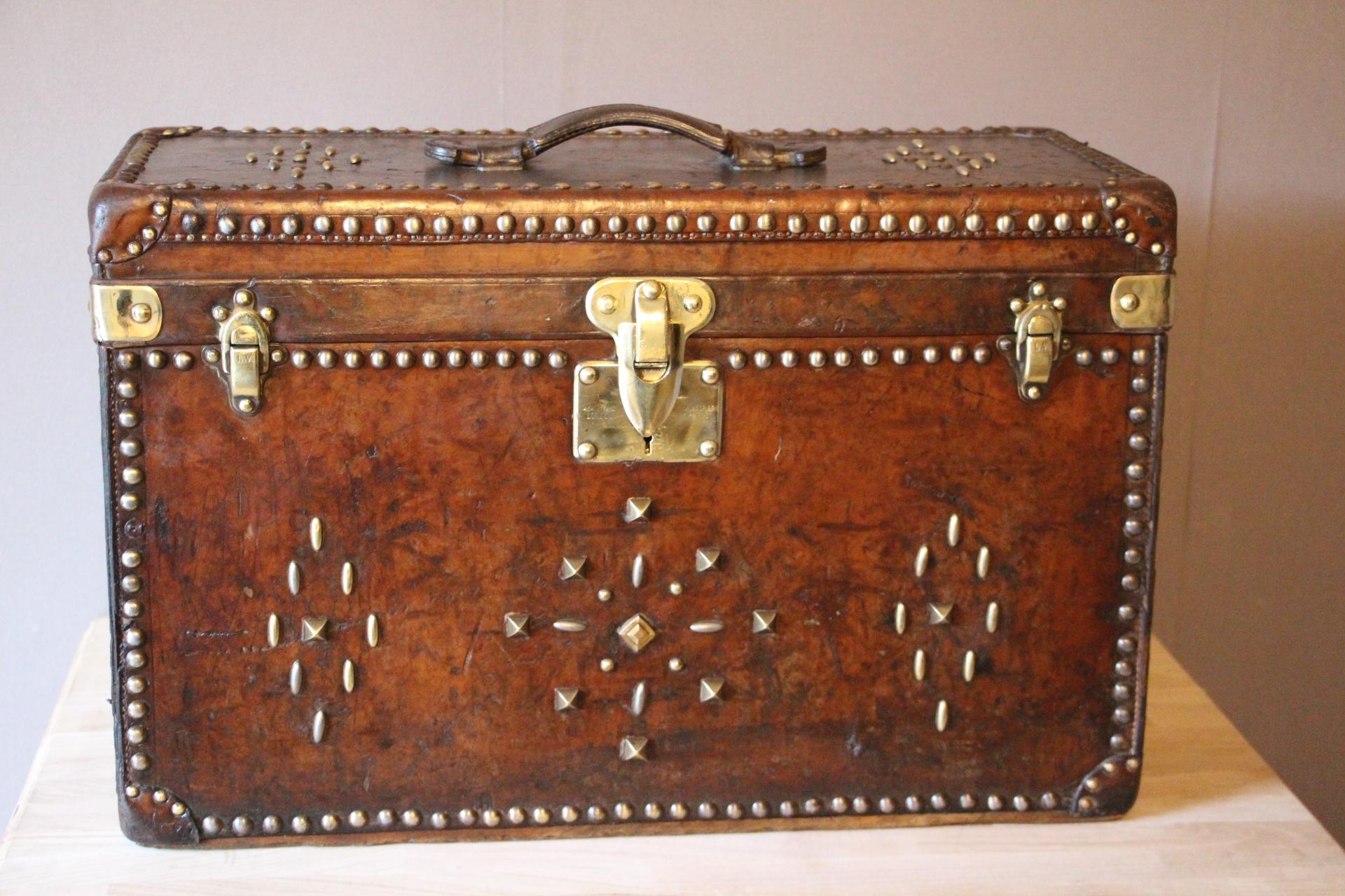 This Louis Vuitton trunk is very unusual by its dimensions and also due to the fact it is all leather. Leather has got a very nice and very warm patina. 
All solid brass Louis Vuitton stamped lock and clasps.
Design made with studs is not