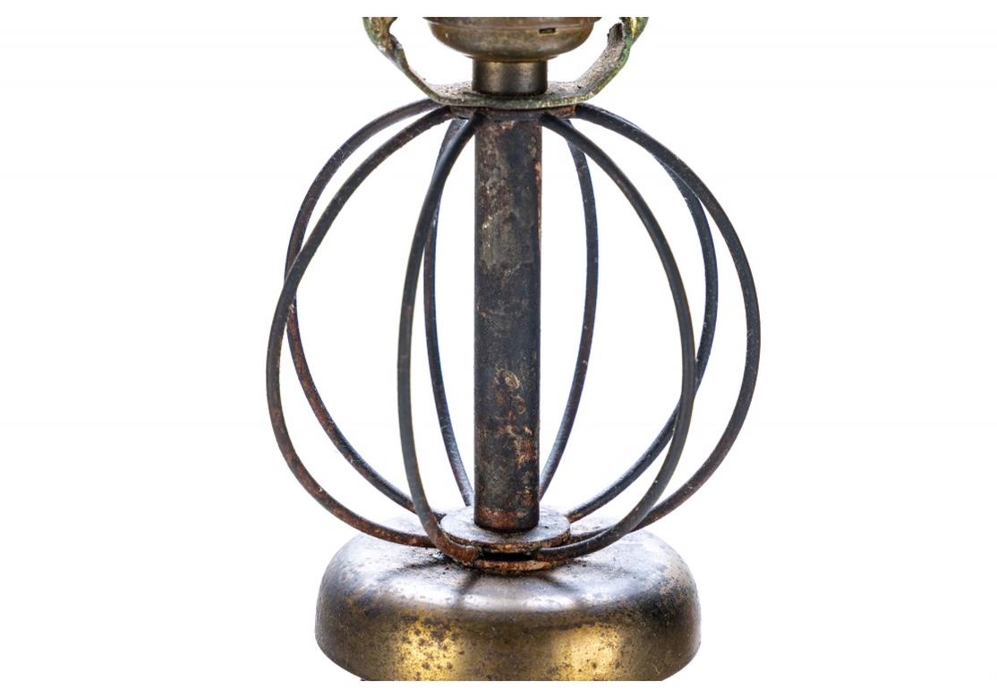 Paire de lampes de table en métal noir et doré des années 1950-1960, en parfait état de fonctionnement. La paire a des bases en anneau à partir desquelles trois tiges rejoignent une cage ronde en fil de fer vers le haut. 
Chaque lampe mesure 7