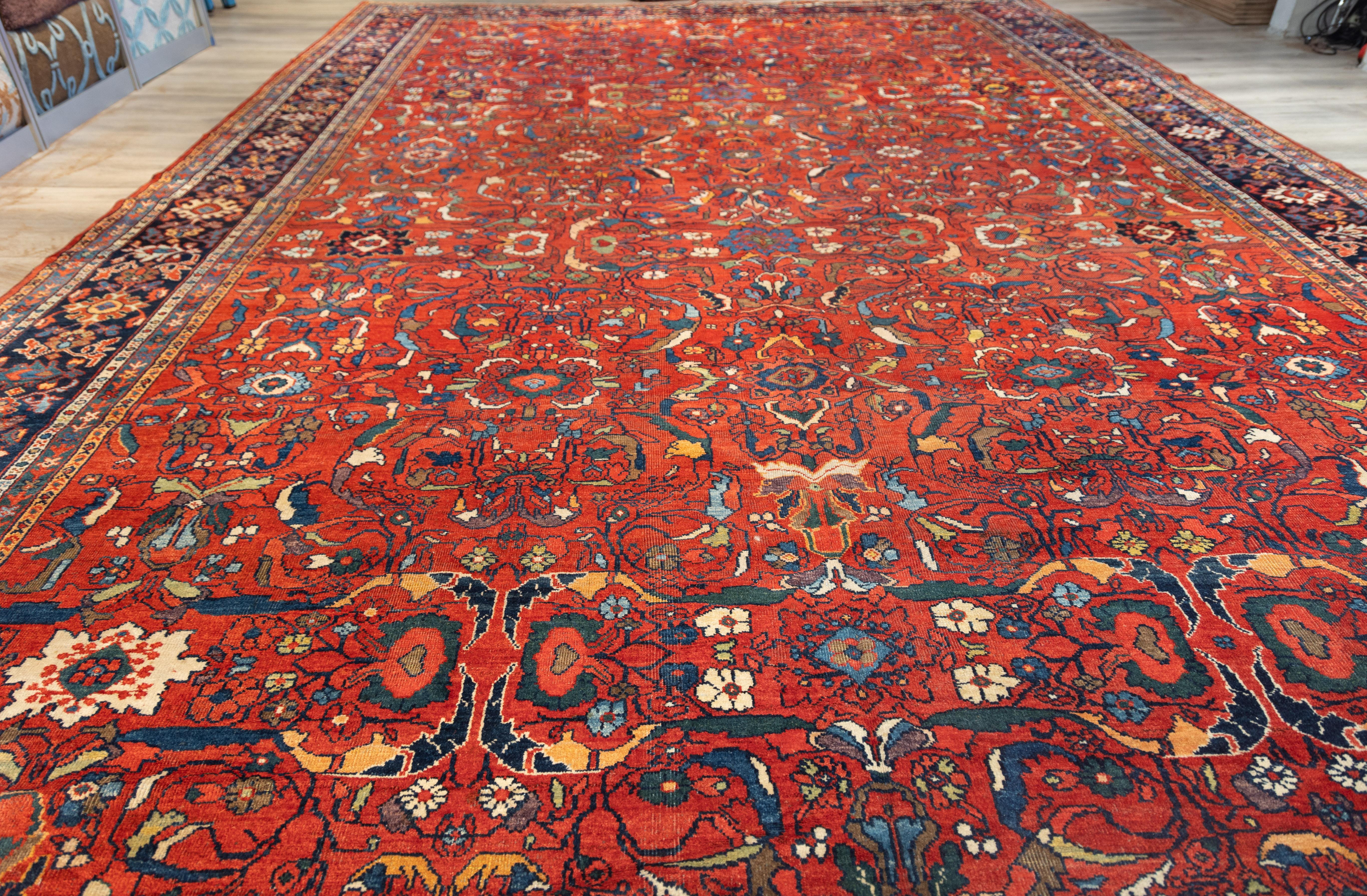 Large Sultanabad featuring an allover lattice of palmettes and floral sprays on a saturated red field. The design is densely packed with large rosettes, angular vines, and curling saz leaves, rendered in navy, ivory, green, and gold tones. The